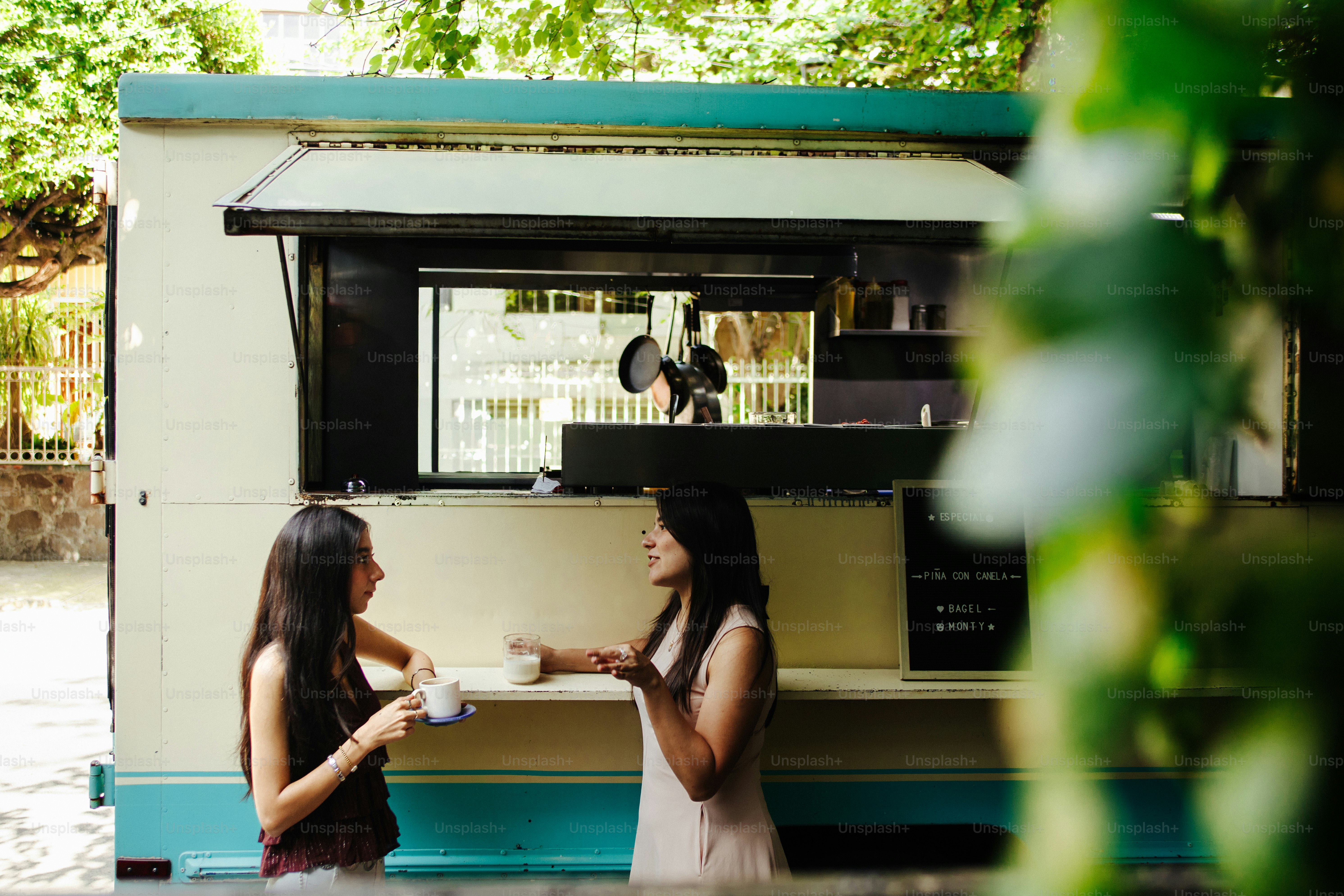 Zwei Frauen, die draußen vor einem Kaffee-Food-Truck sprechen