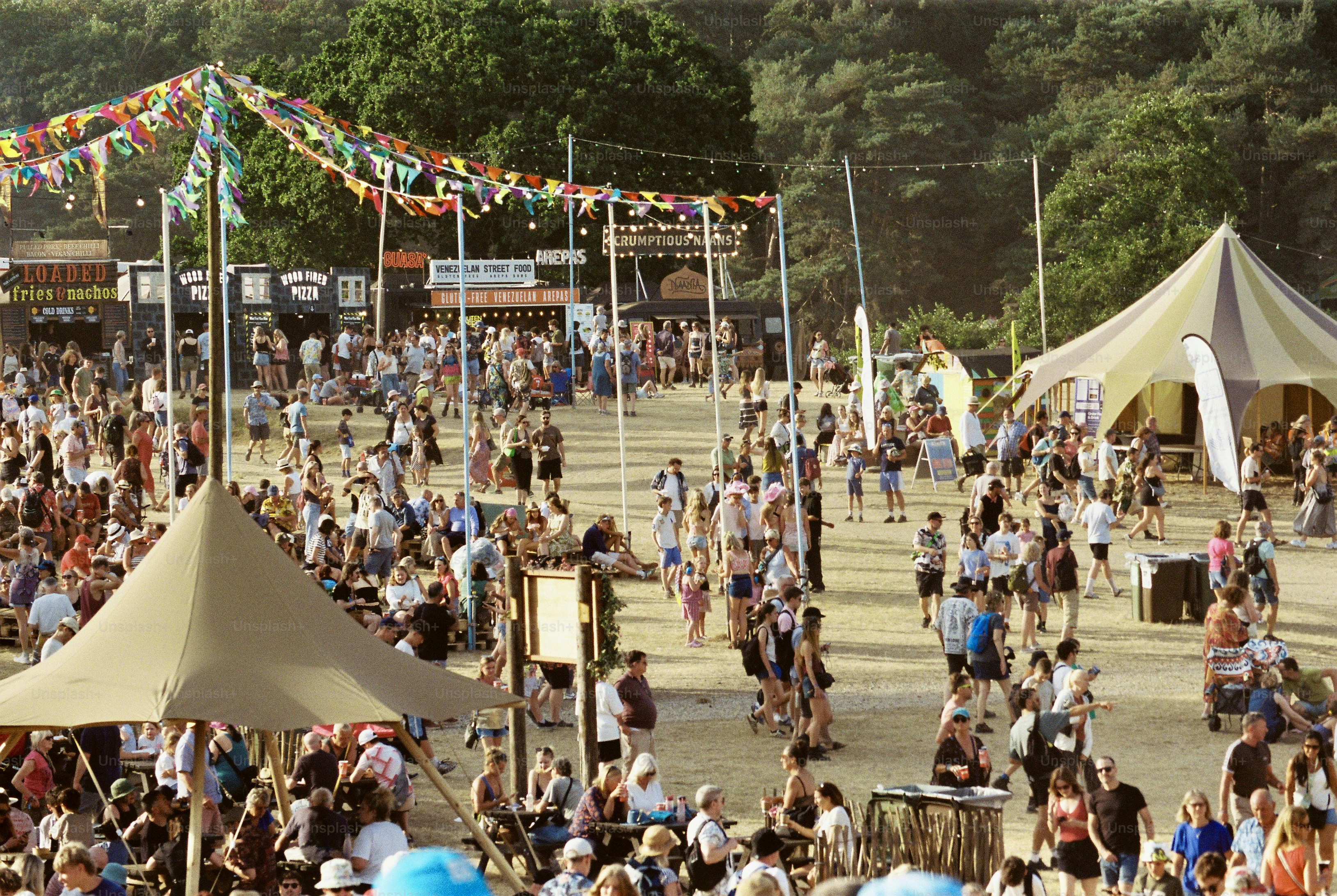 Festival crowds, bunting, and tipi tents at food stalls