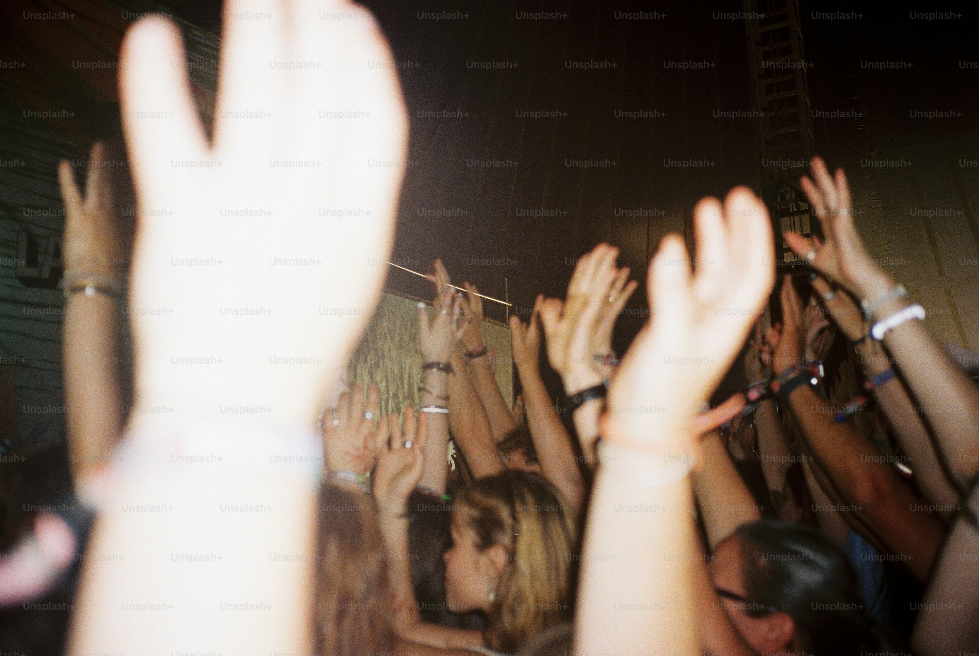 Blurred hands and wristbands above night festival crowd