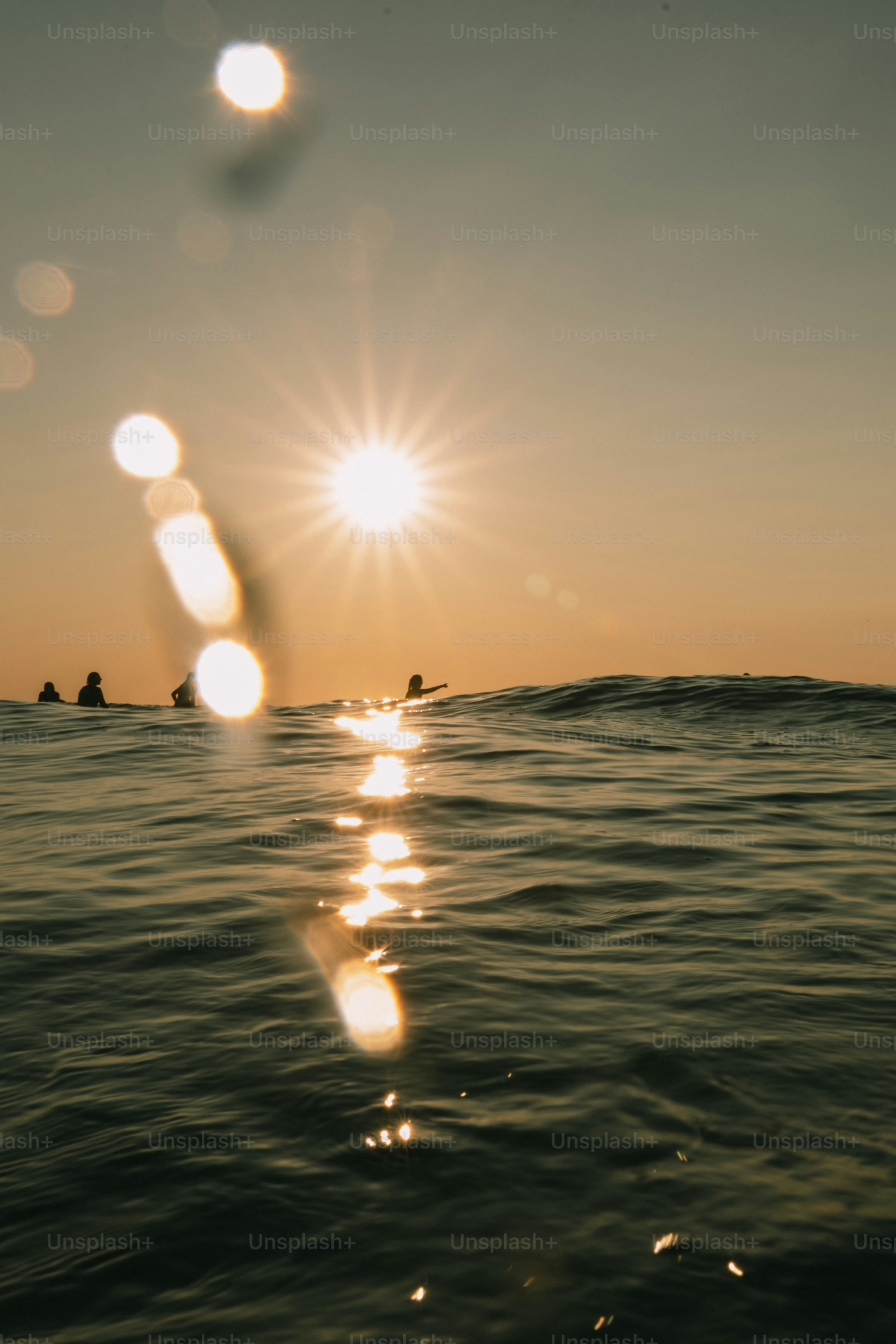 Sonnenuntergang über dem Ozean mit Surfern