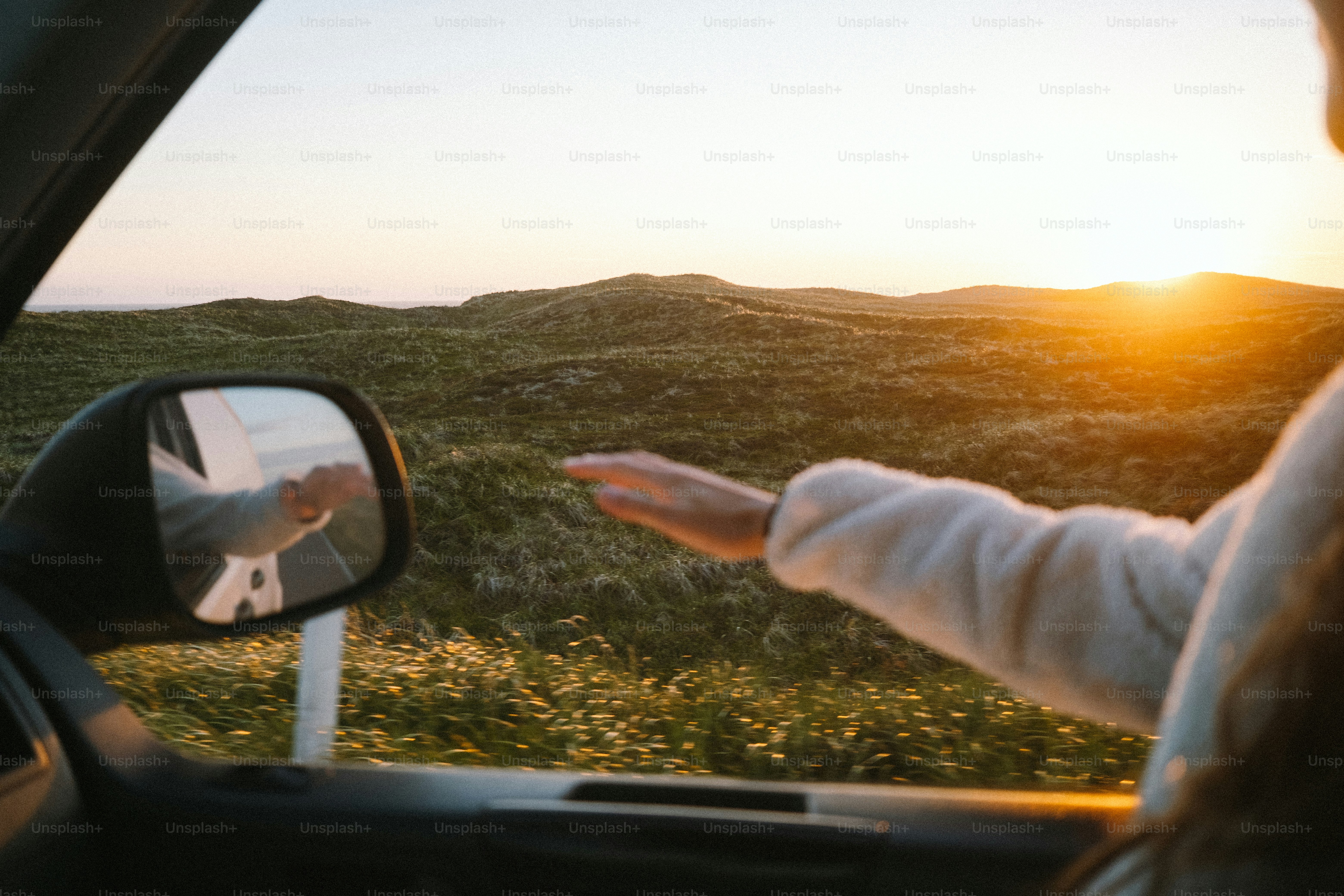 Main attrapant le vent par la fenêtre de la voiture, paysage au coucher de cheval