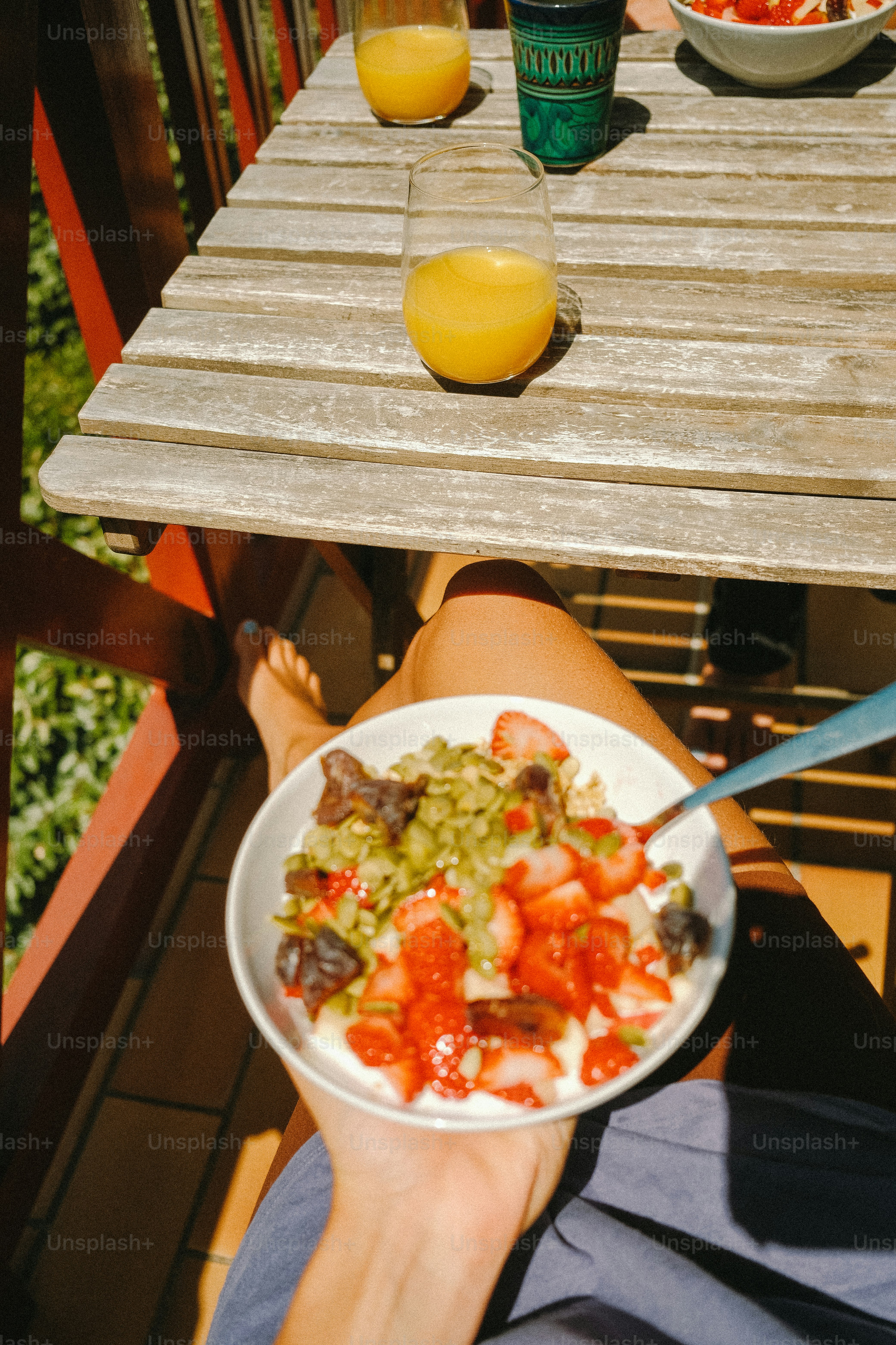 Bol petit-déjeuner aux fraises tenu sur un balcon ensoleillé