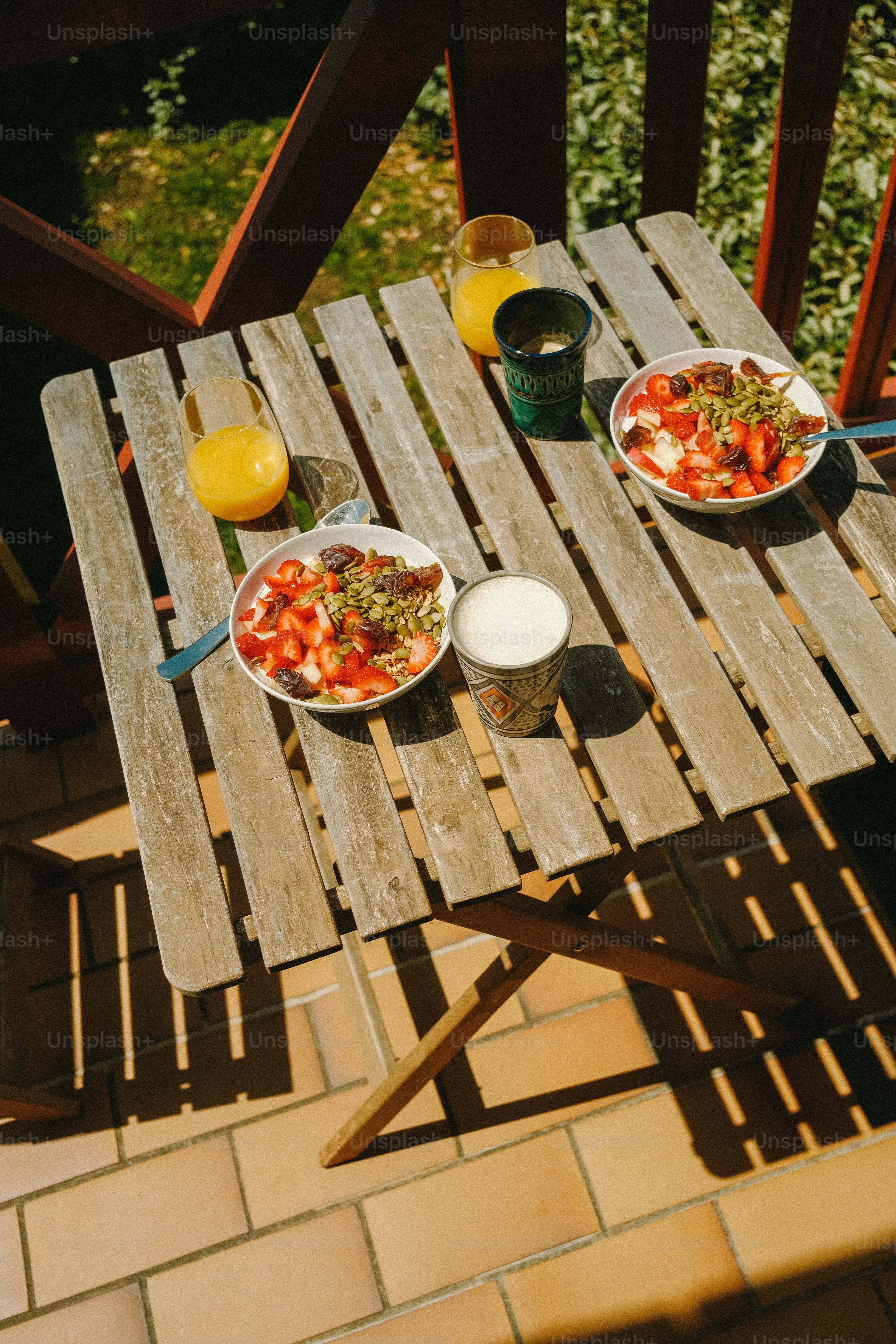 Erdbeer-Frühstücksschalen und Orangensaft auf dem Balkontisch