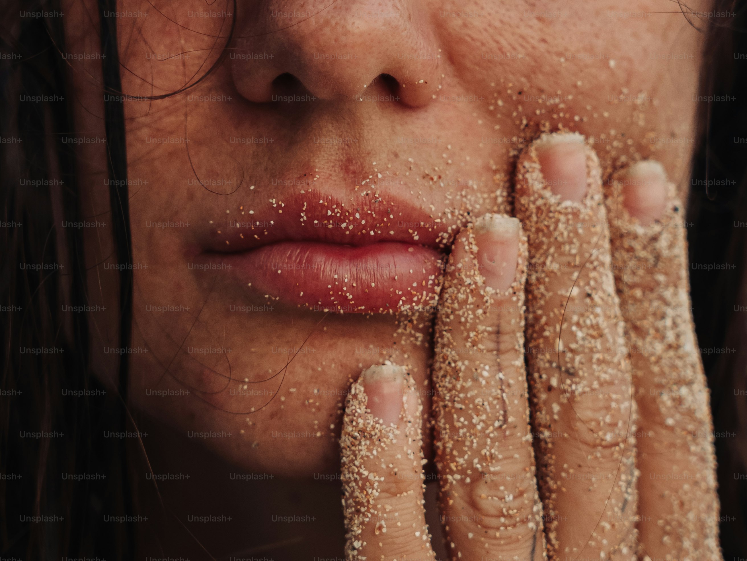 Die Lippen und die Hand der Person sind mit Sand bedeckt