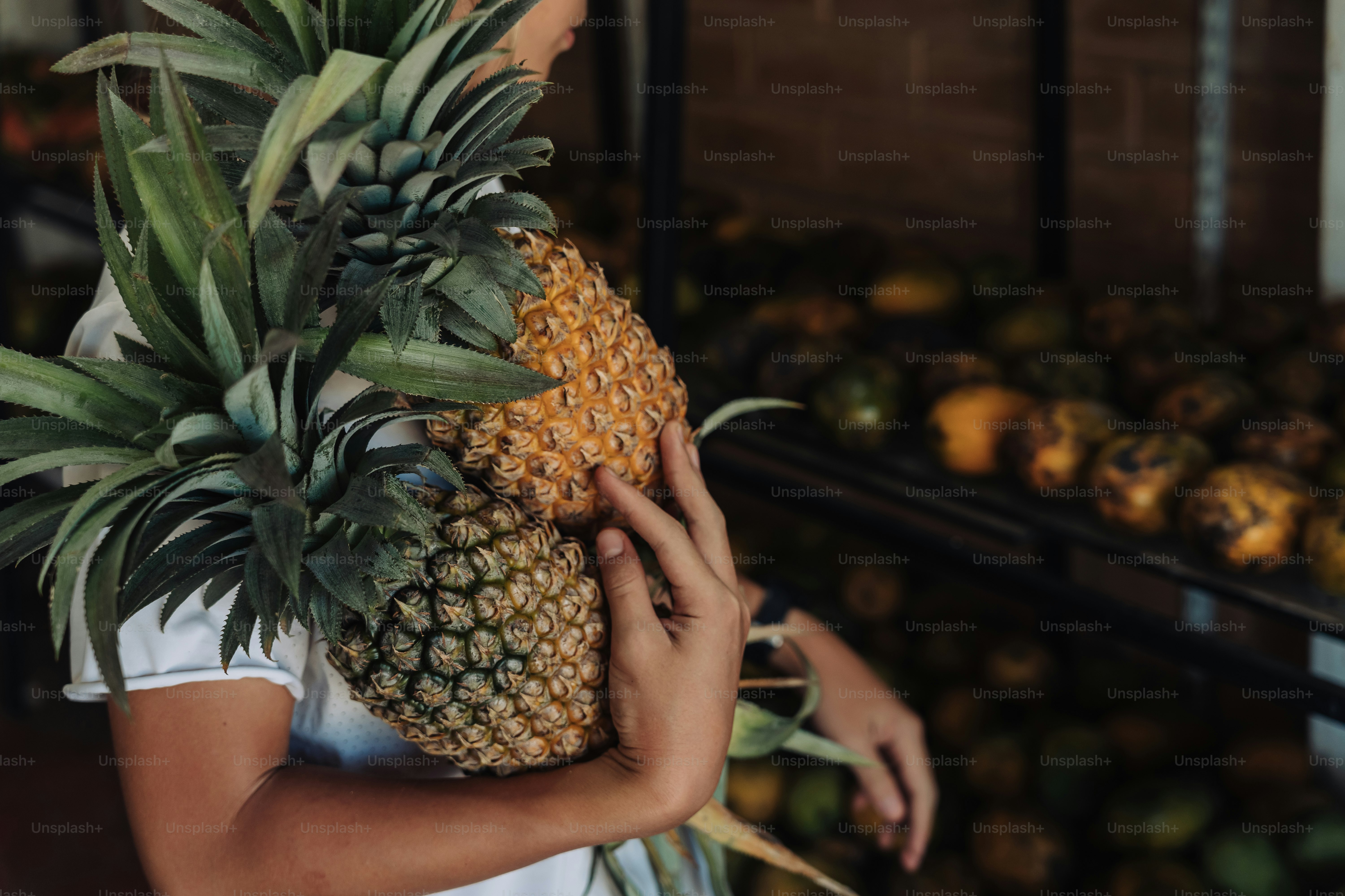 Person, die zwei frische Ananas auf einem Markt hält