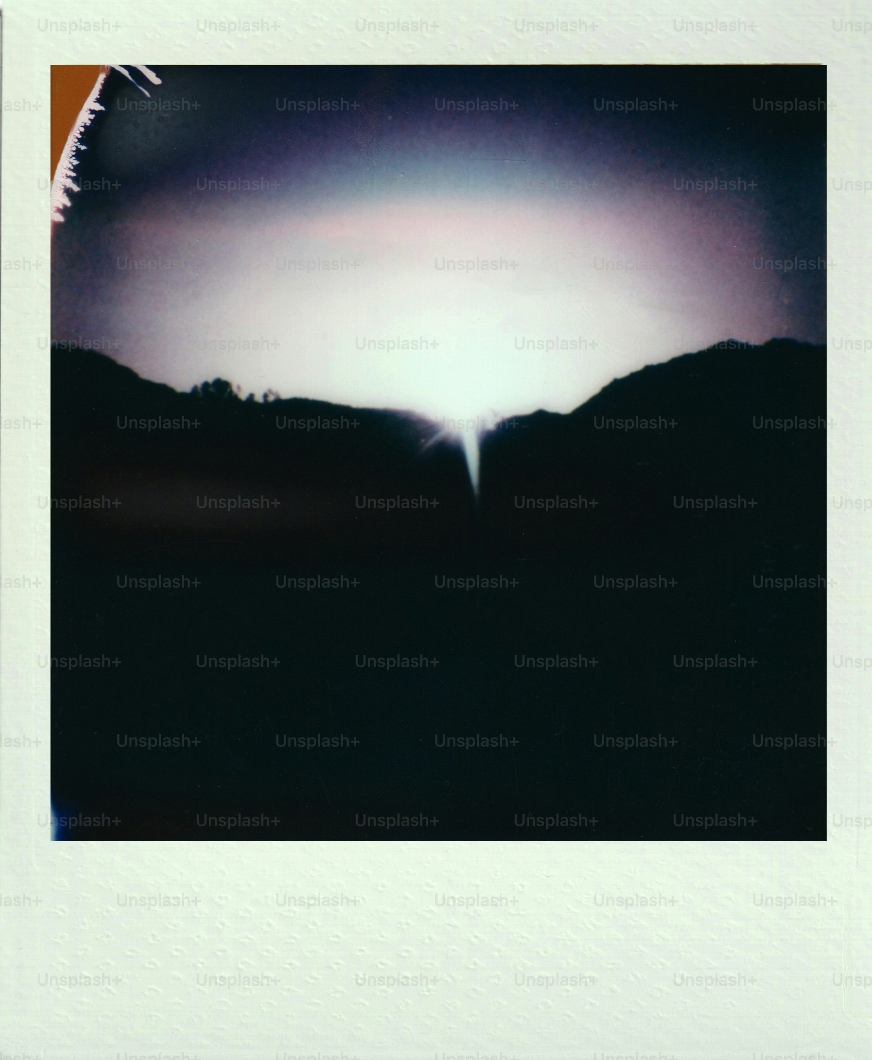 Vintage polaroid of sunlight streaking over dark mountains