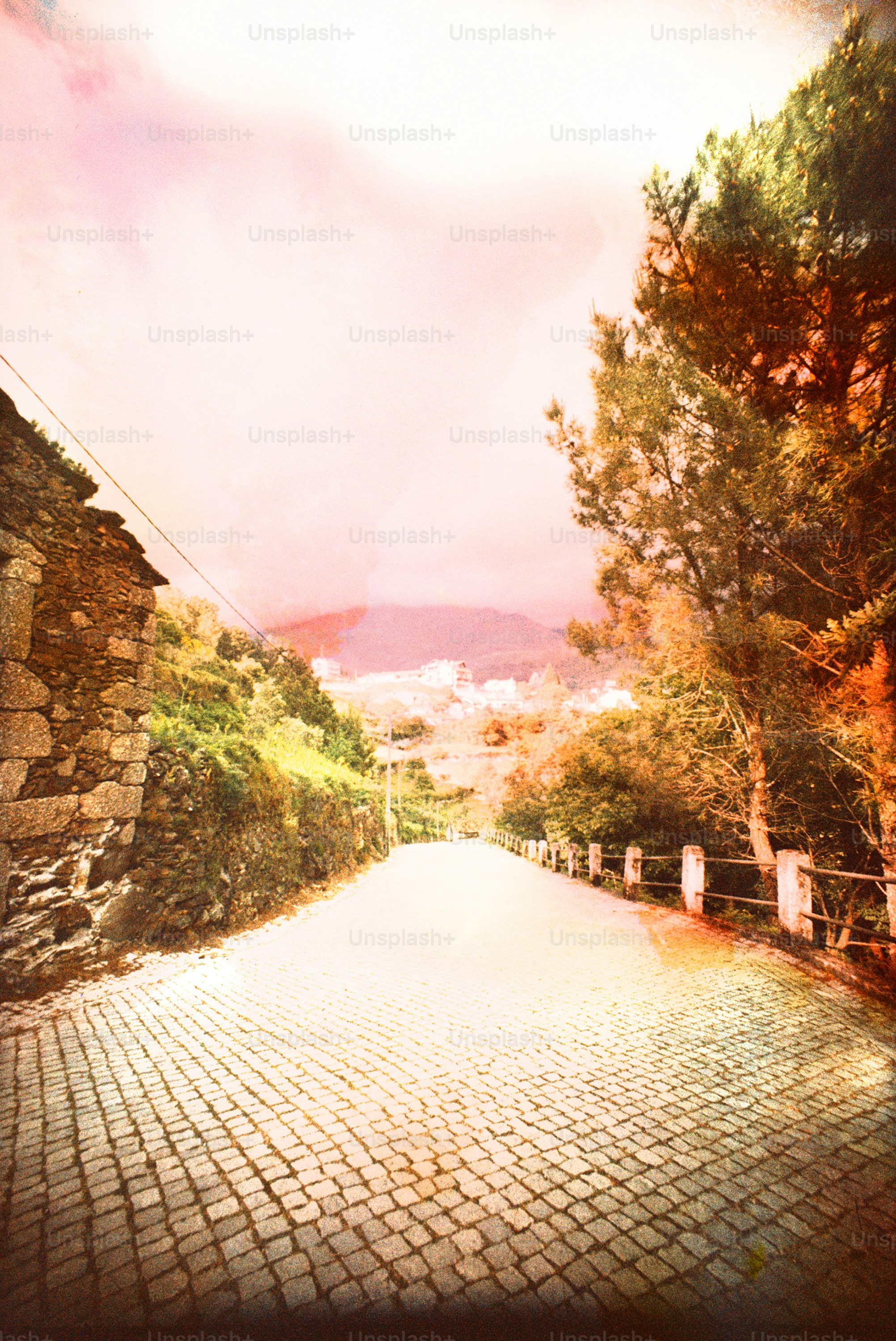 Route pavée menant au village sous un ciel rose