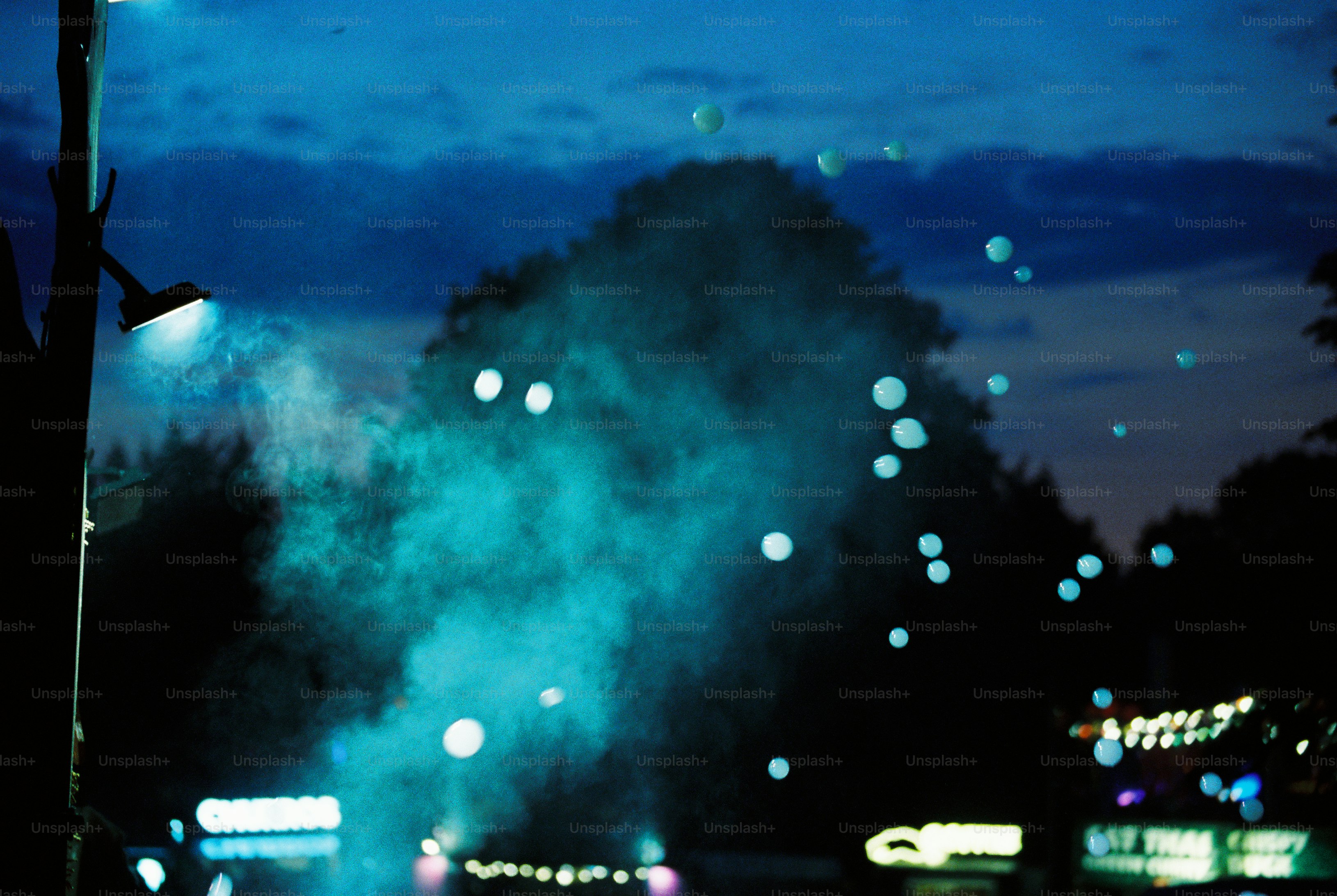 Fumée bleu-vert, bulles et panneaux lumineux au crépuscule