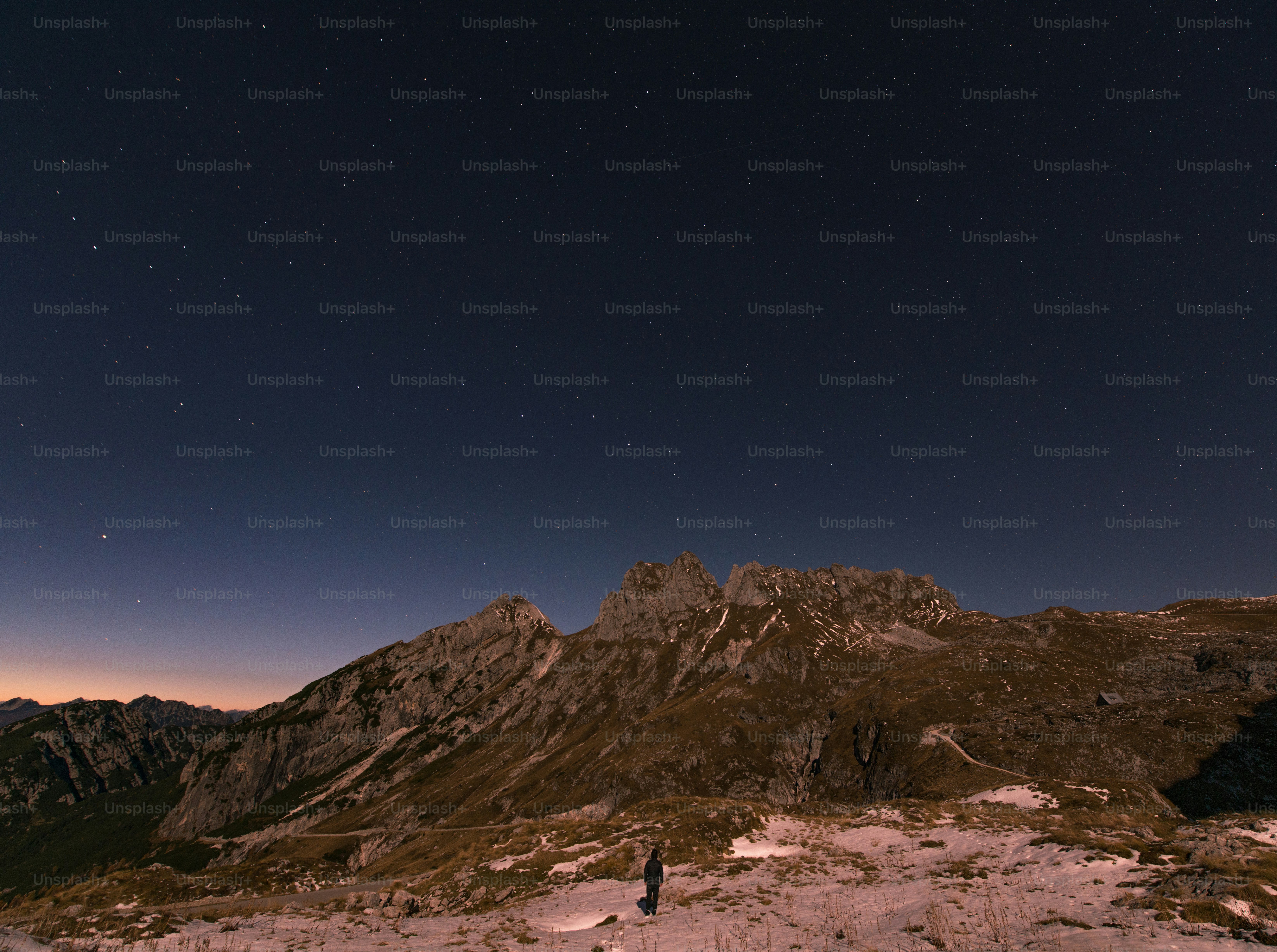 Starry night above mountains with lone person
