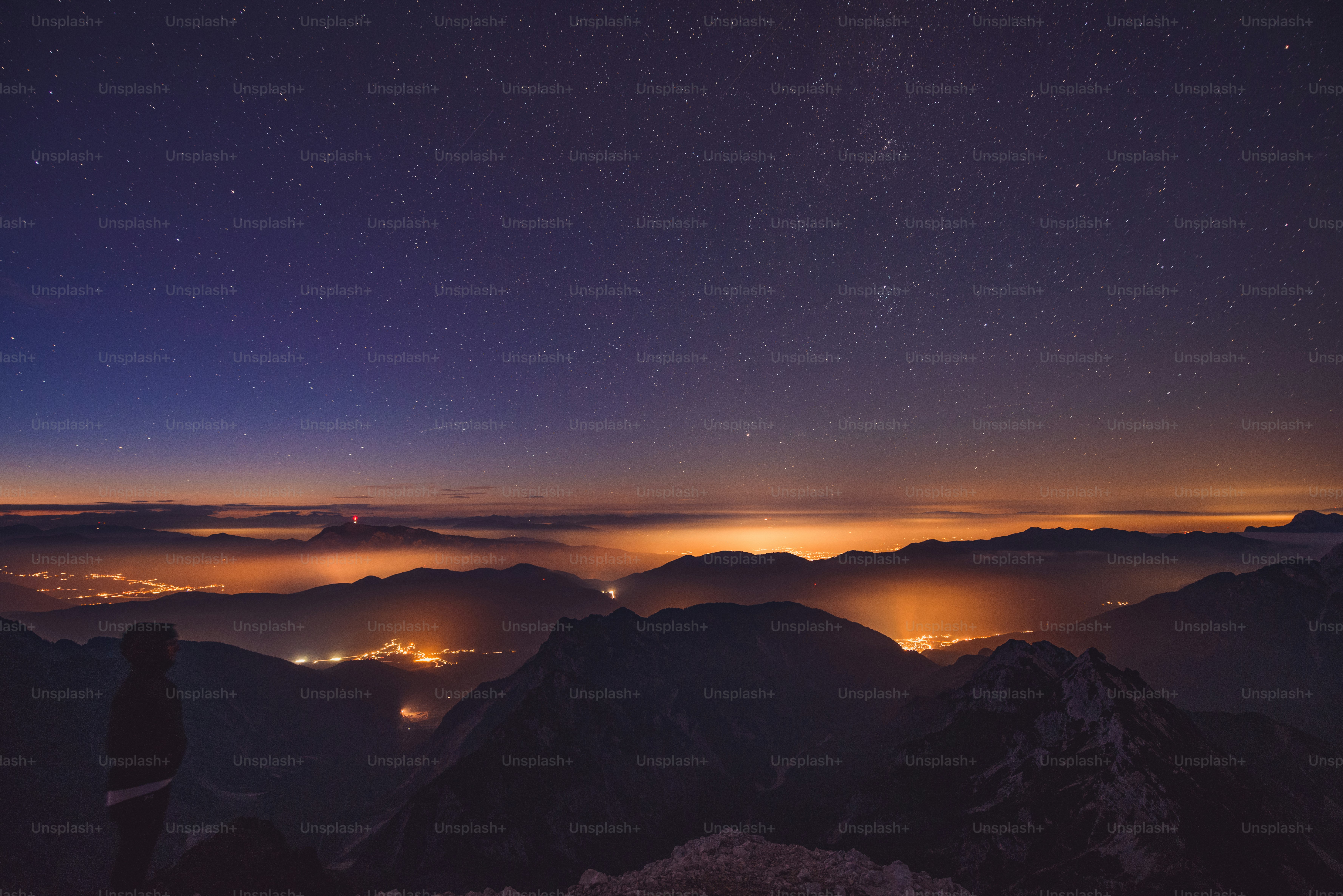 Person under starry night sky overlooking city lights