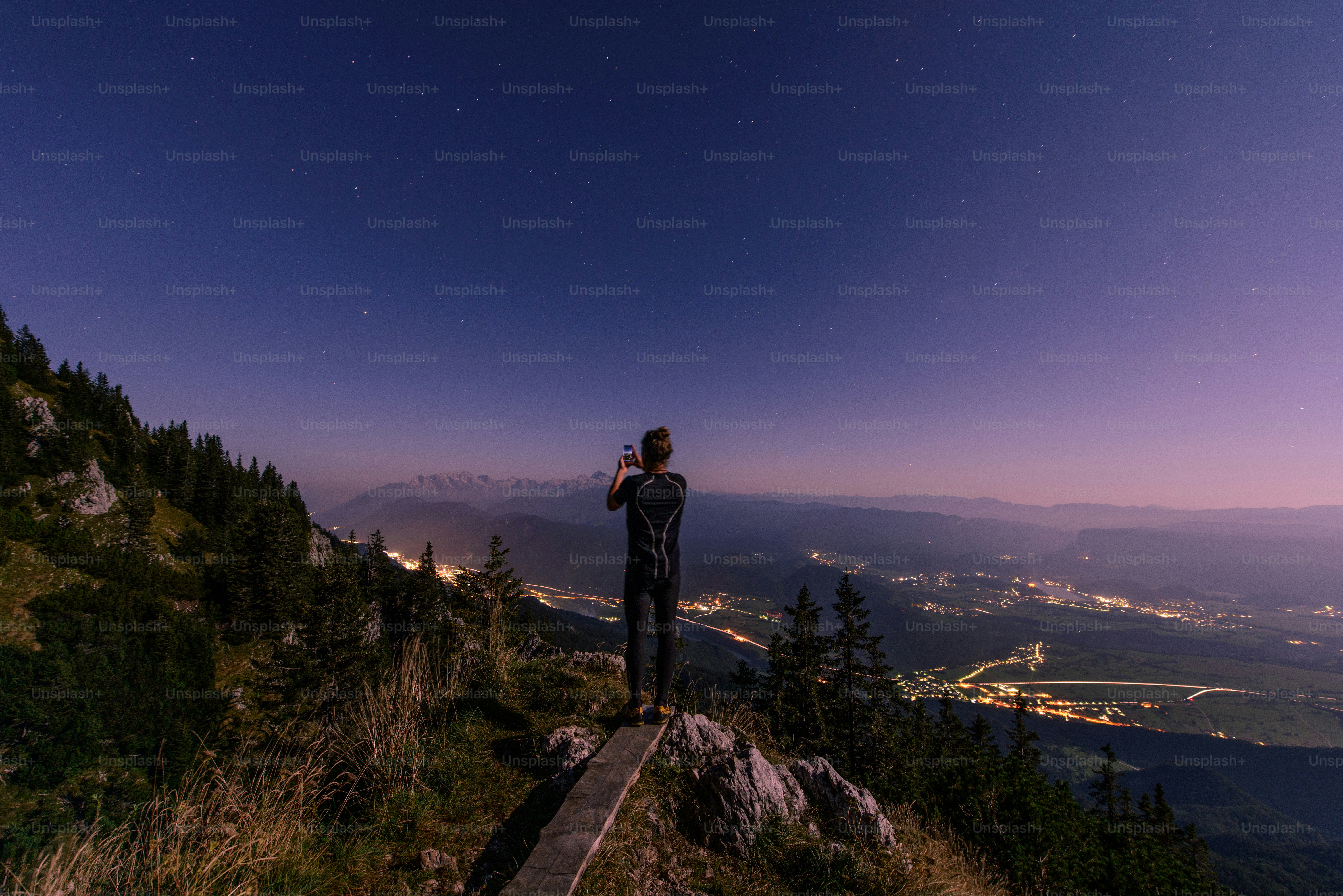 Man on mountain looking at starry night sky