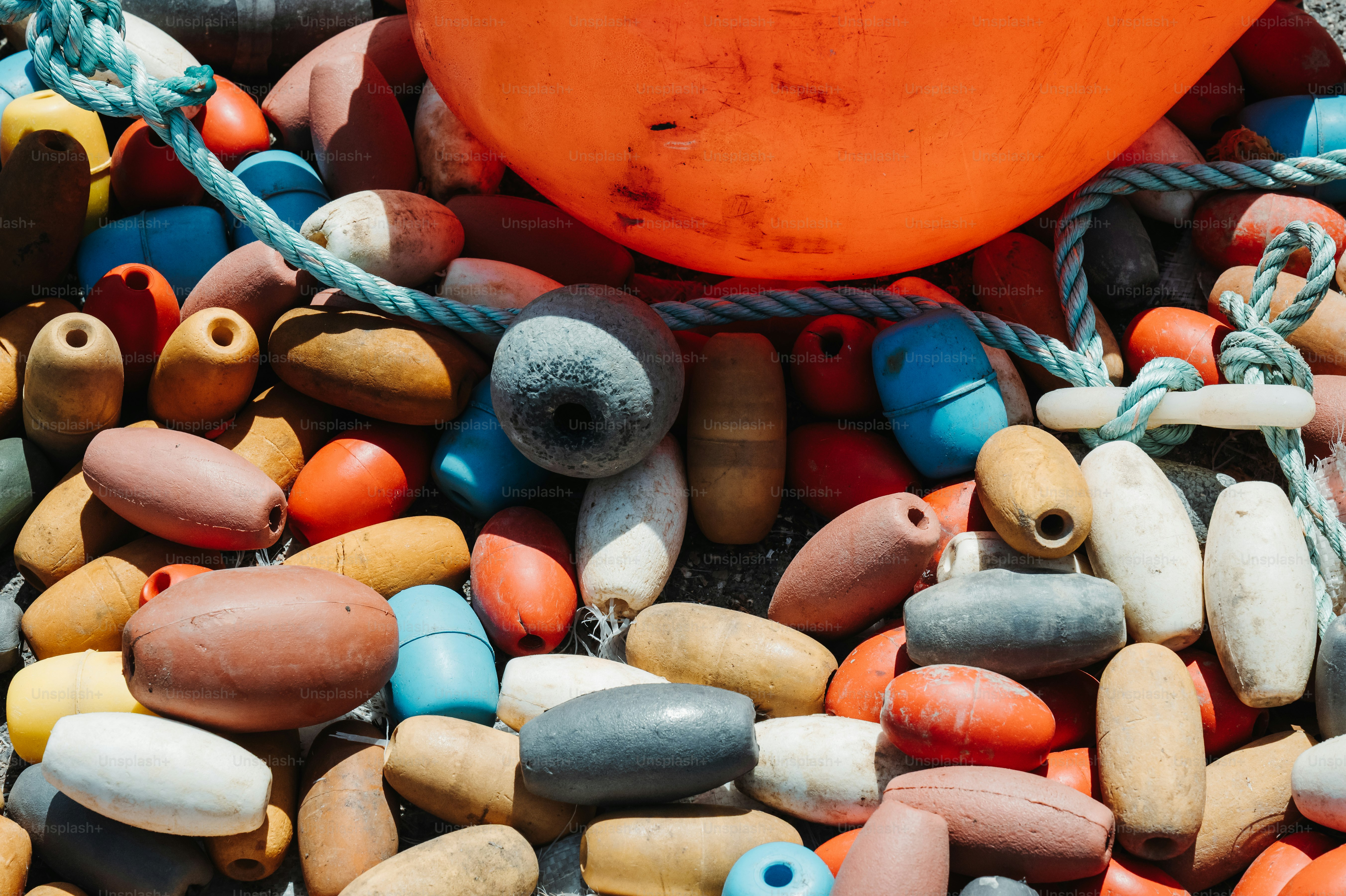 Un tas de filets de pêche colorés flotte et une grande bouée orange avec une corde.