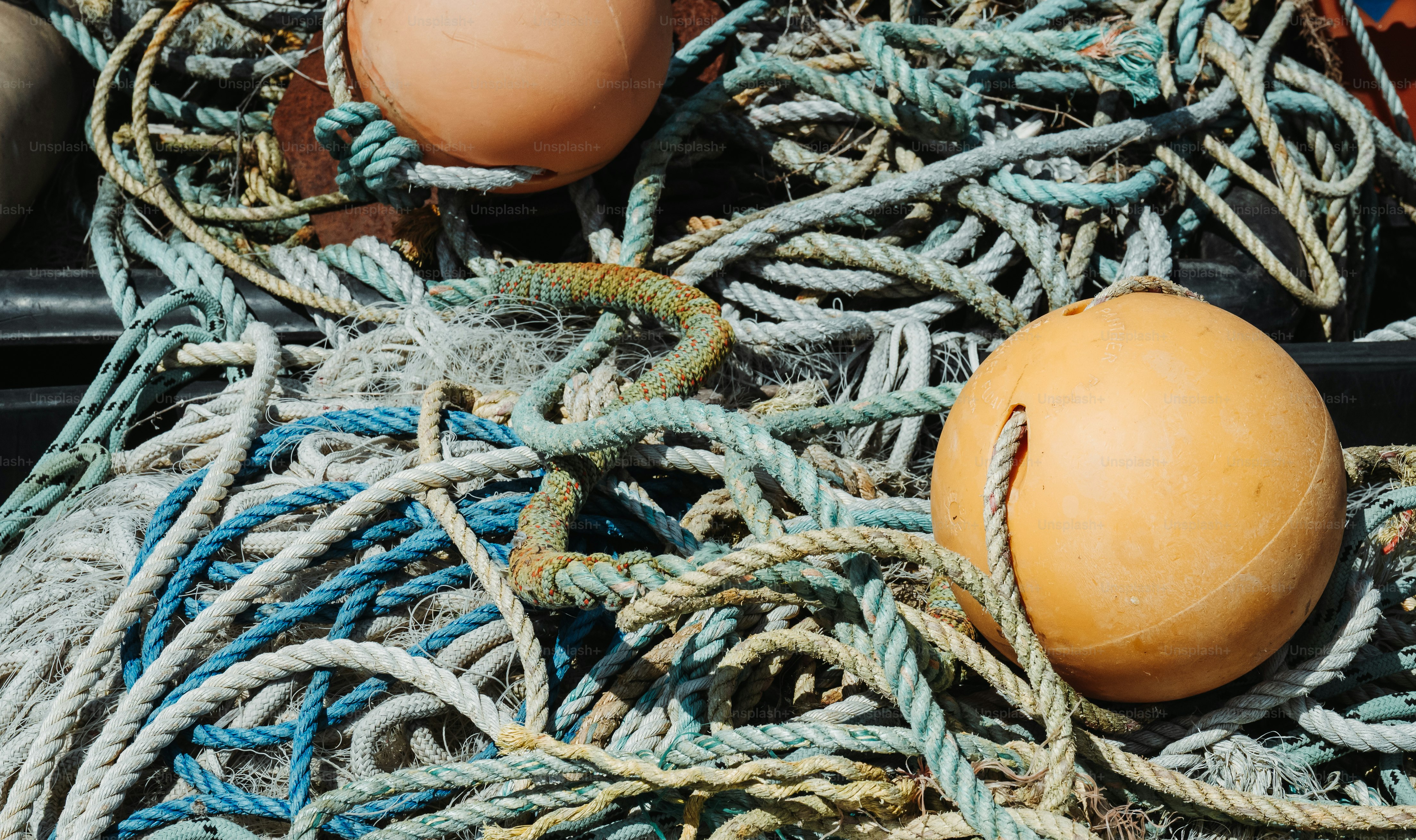 Des cordes de pêche bleues et blanches emmêlées avec deux bouées en plastique orange.