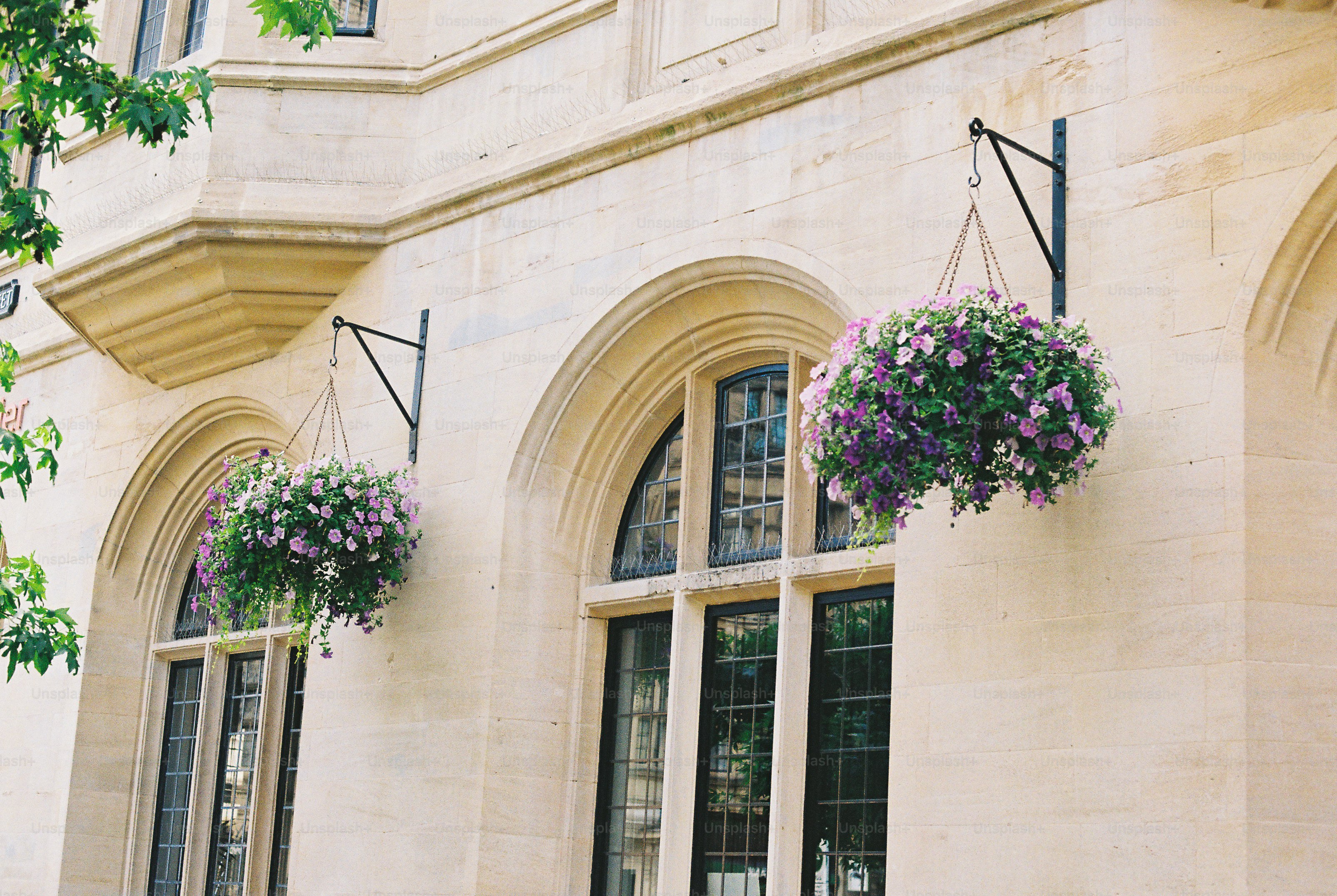 Stone building with arched windows and hanging flower baskets