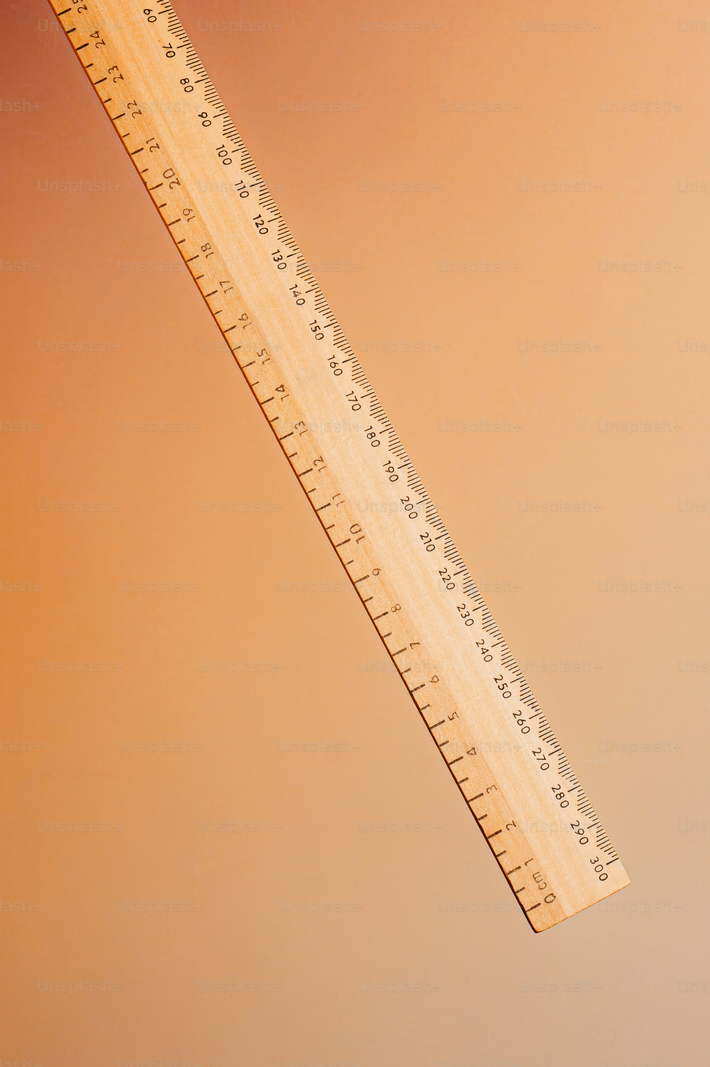 Règle en bois diagonale sur fond orange chaud