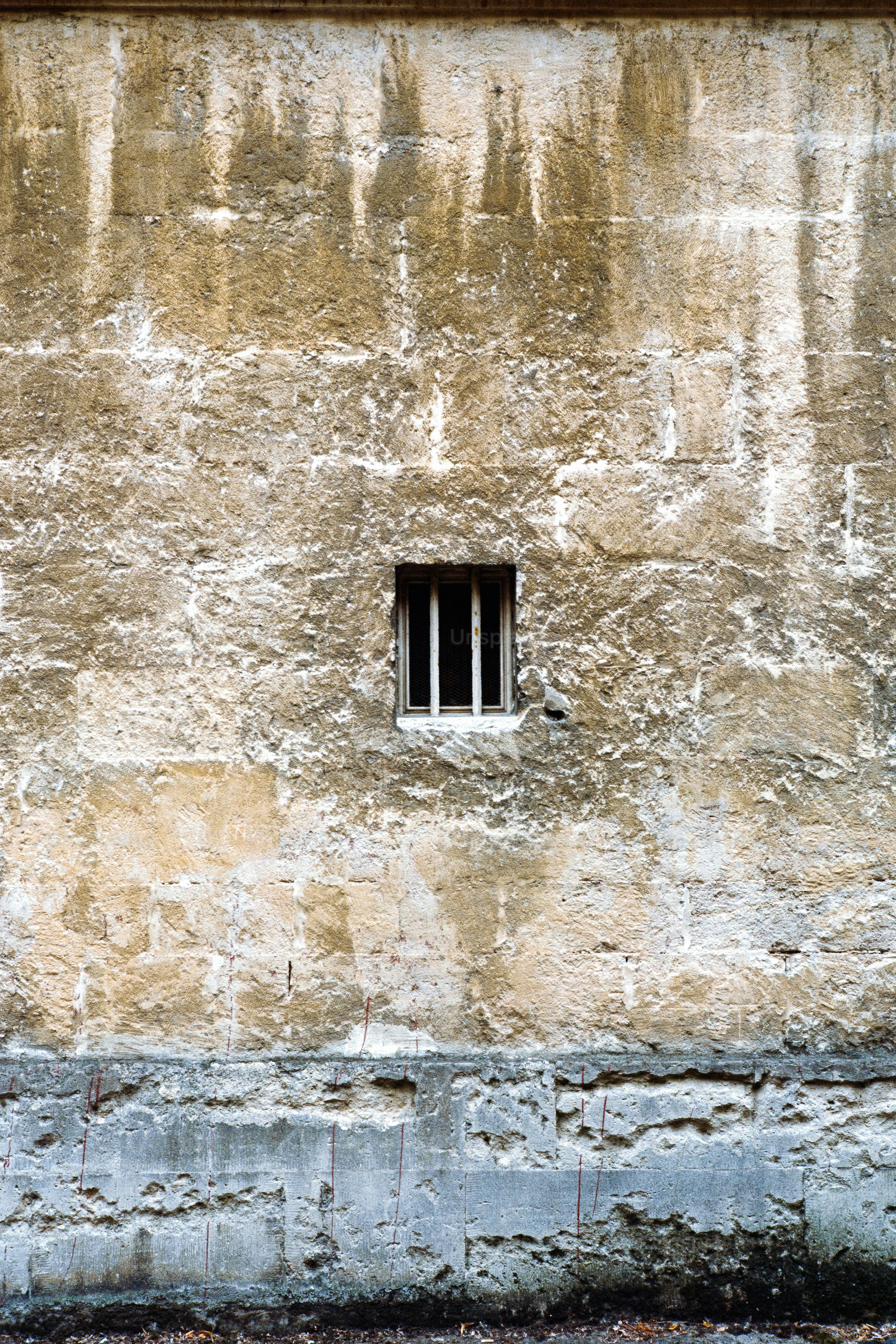 Textured stone wall with small barred window