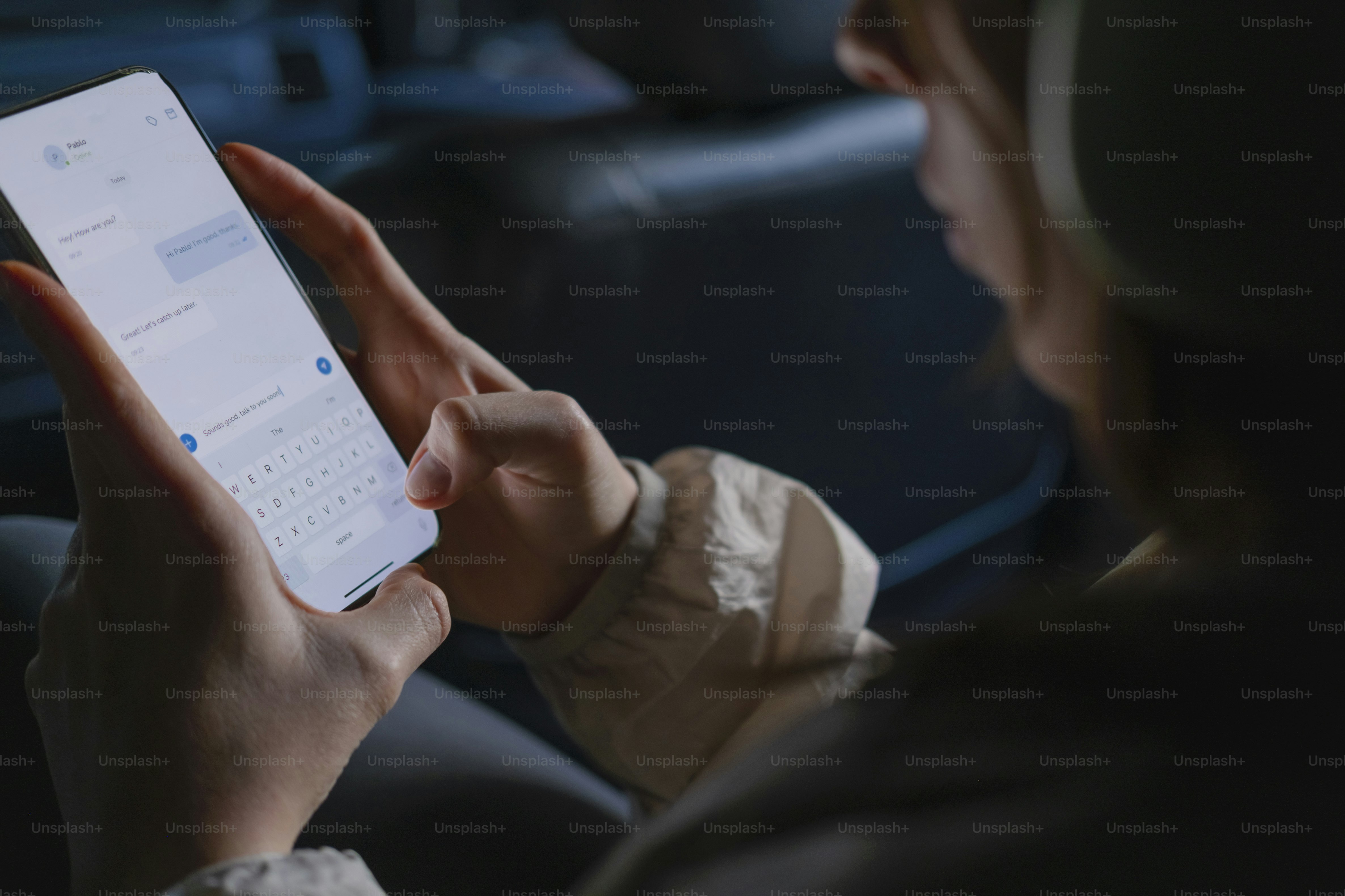Mains tapant un message texte sur l’écran lumineux du smartphone