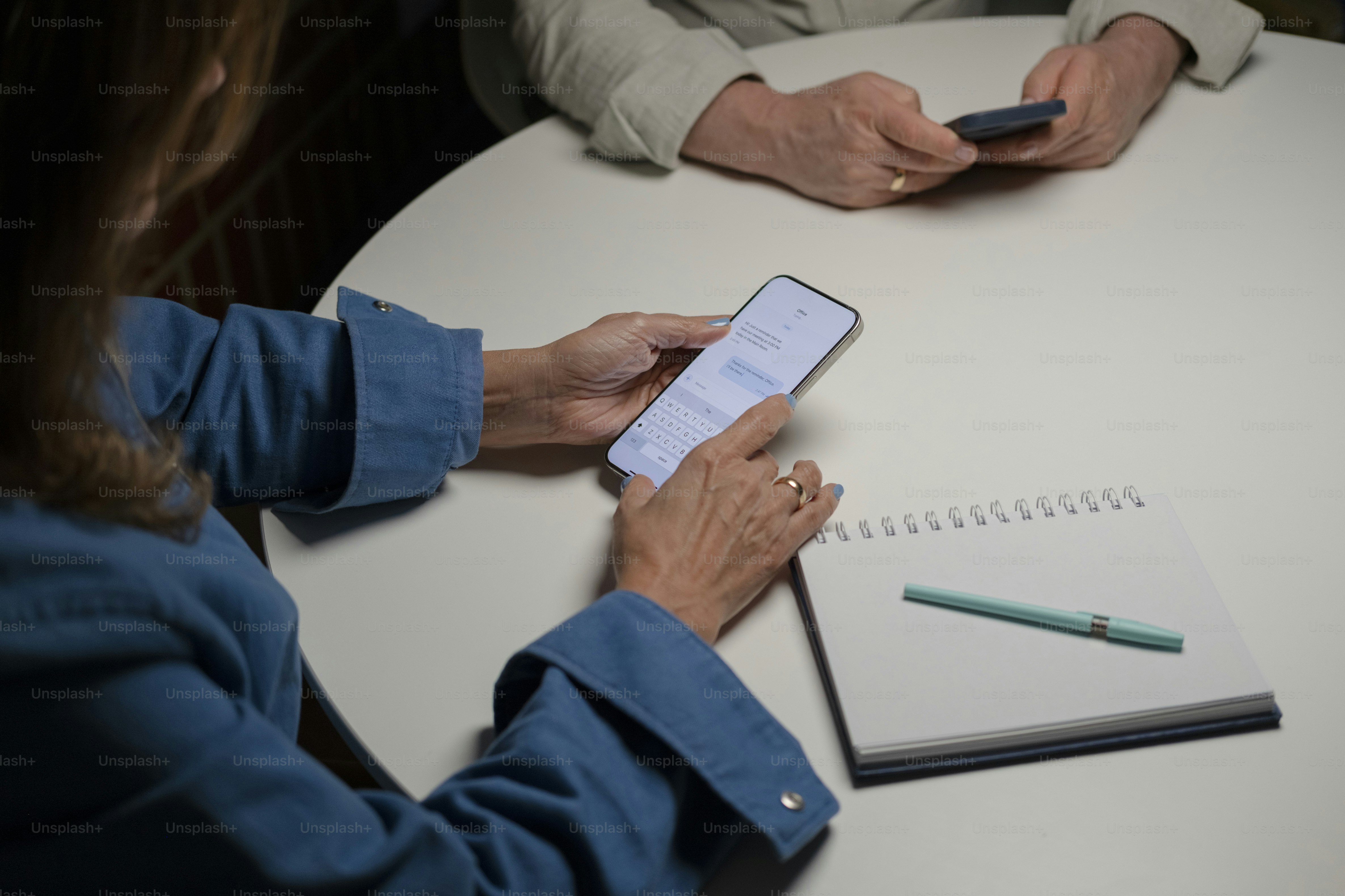 Deux personnes utilisant un smartphone autour d’une table blanche