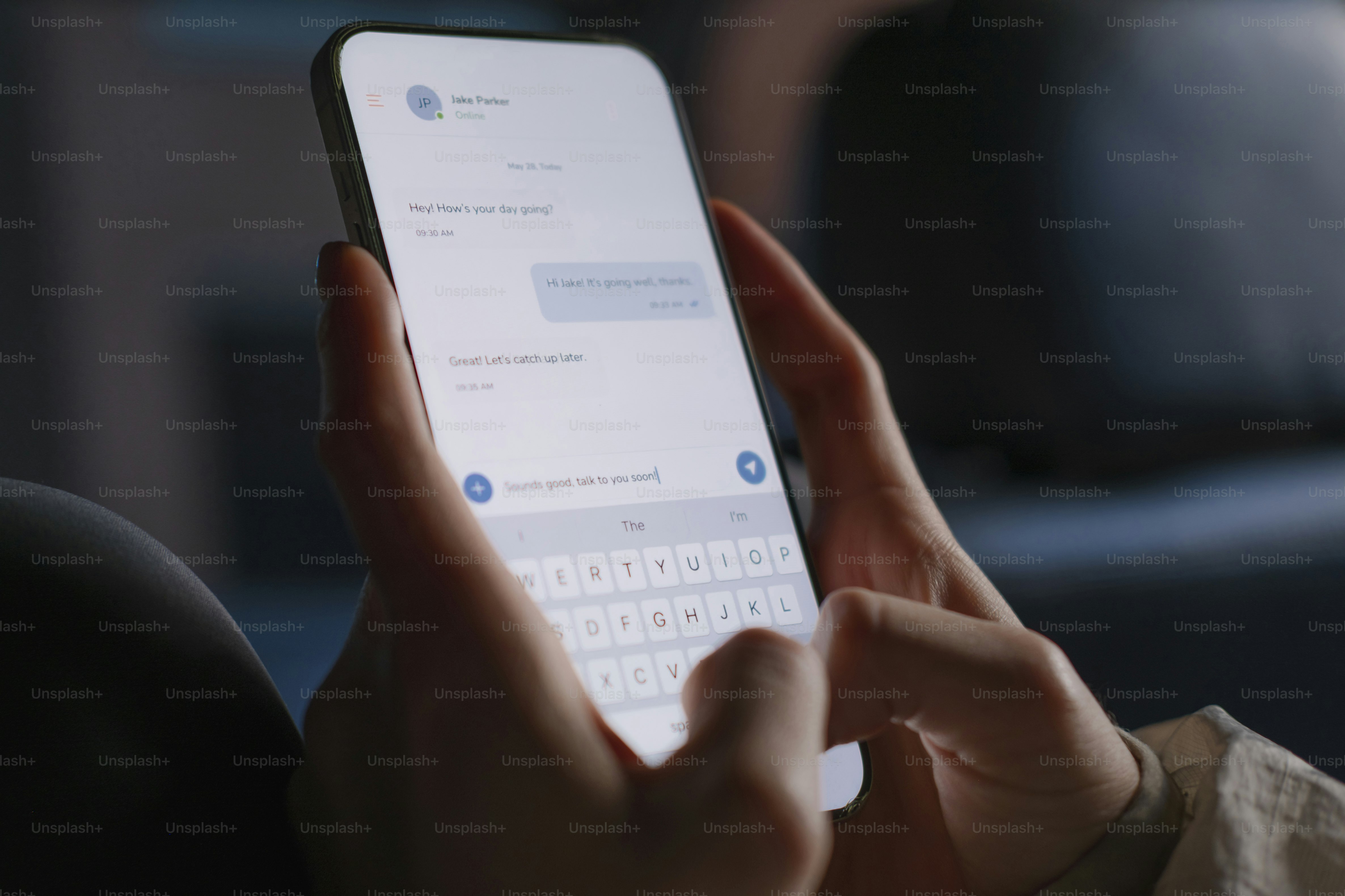 Des mains tapant un message sur un écran lumineux de smartphone