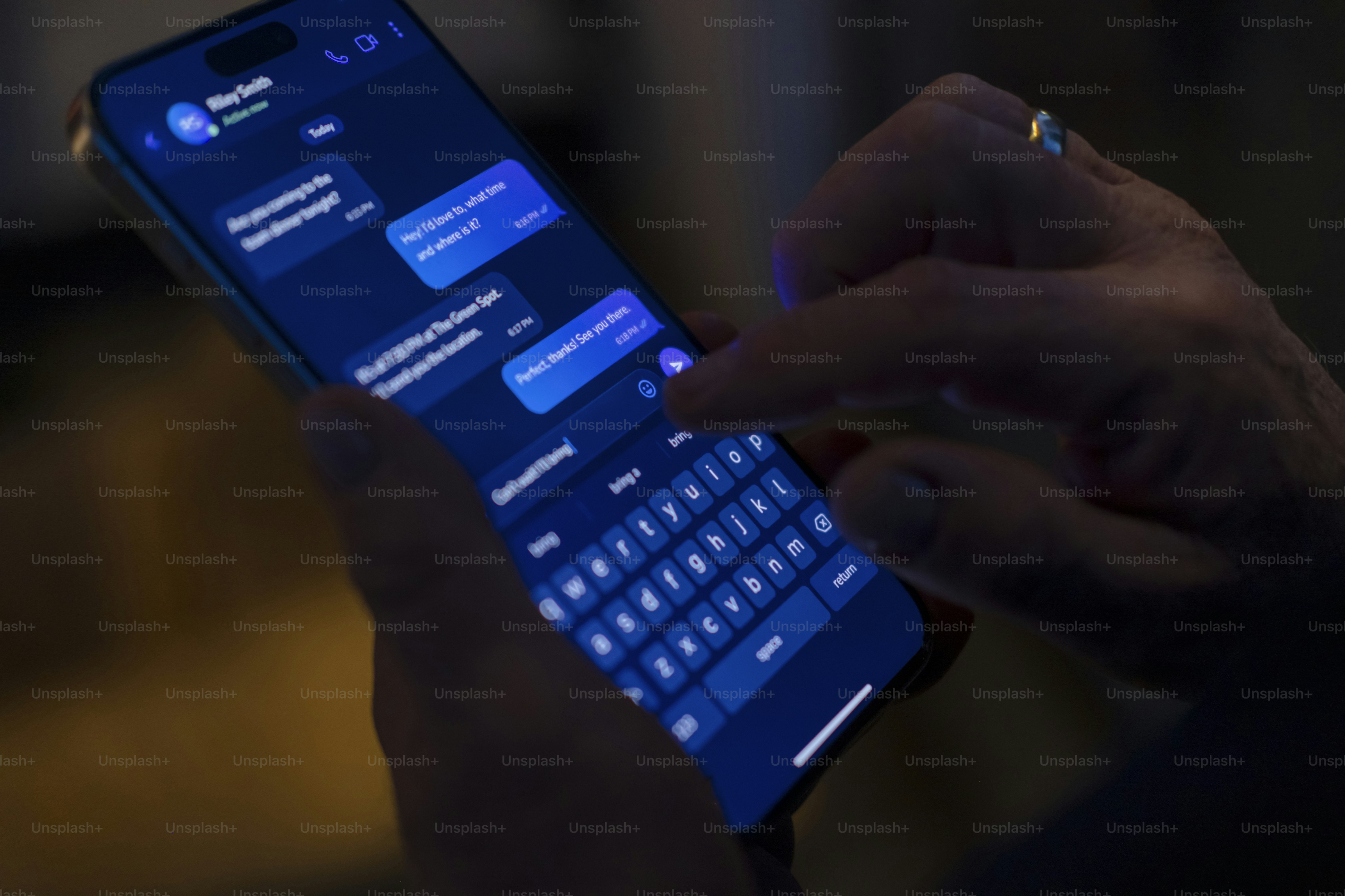 Mains tapant un message sur l’écran lumineux du smartphone