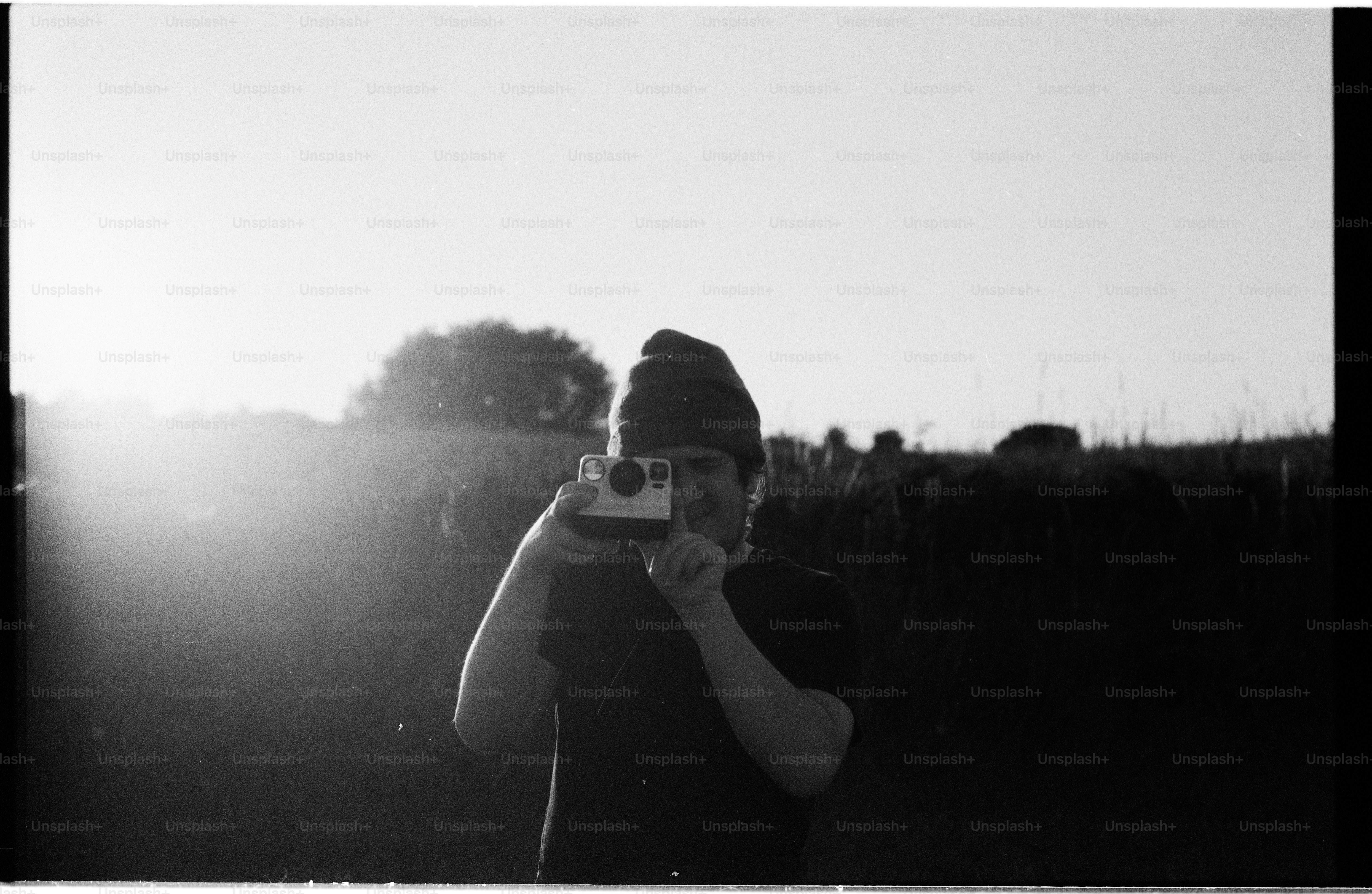 Person holding camera outdoors with bright sun flare