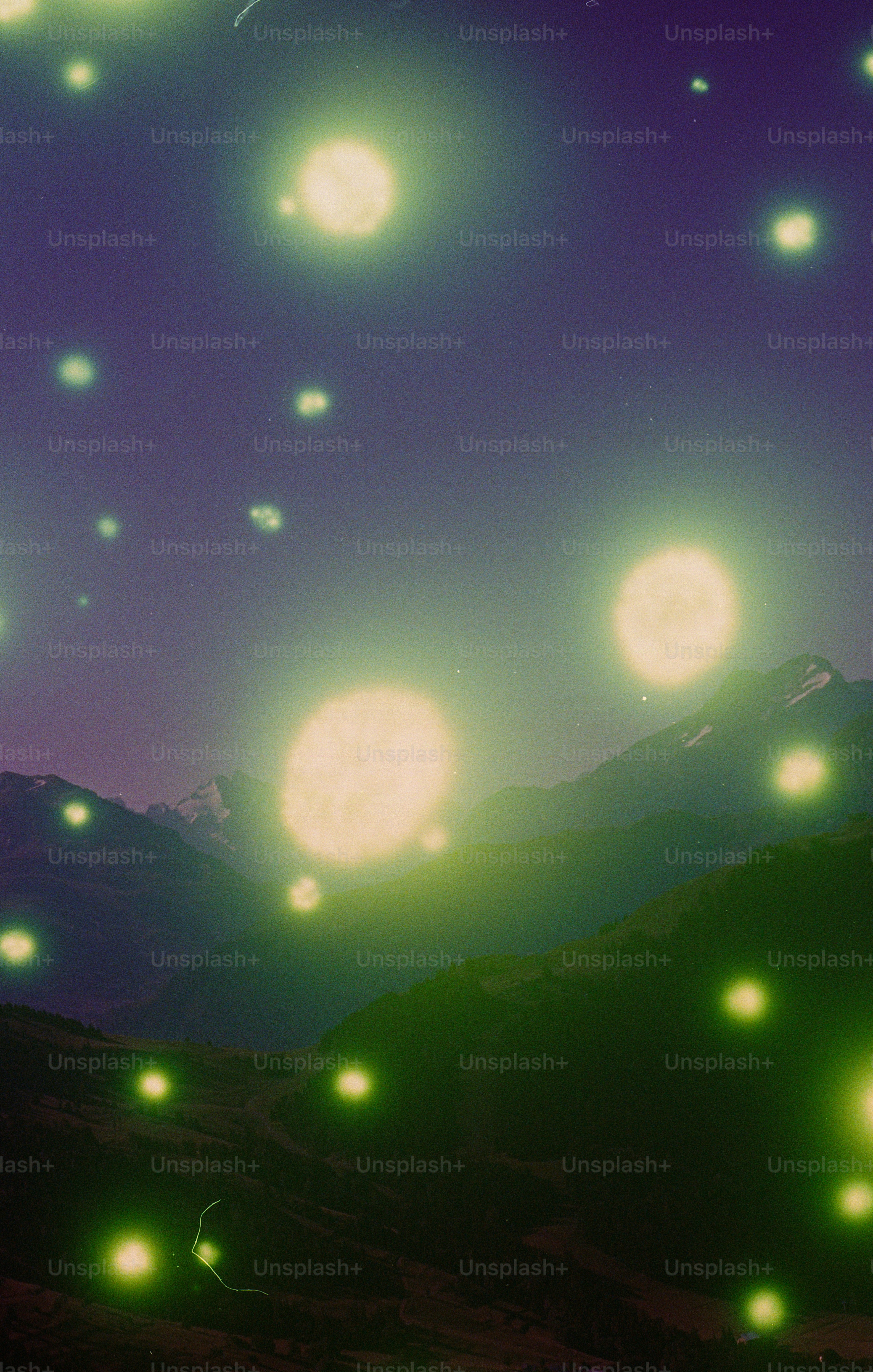 Firefly-like lights illuminate dark mountain landscape