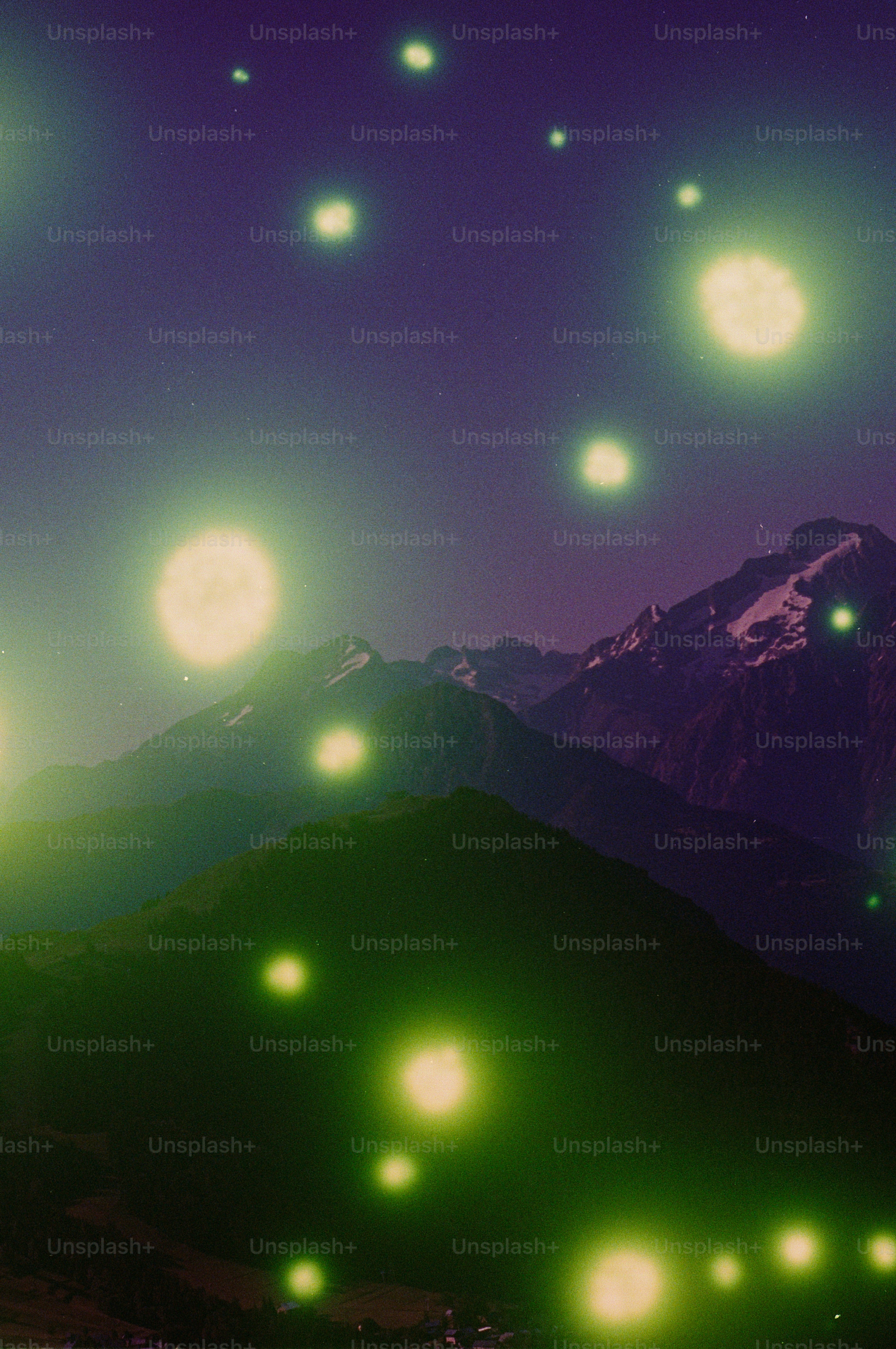 Glowing green orbs above dark mountains at night