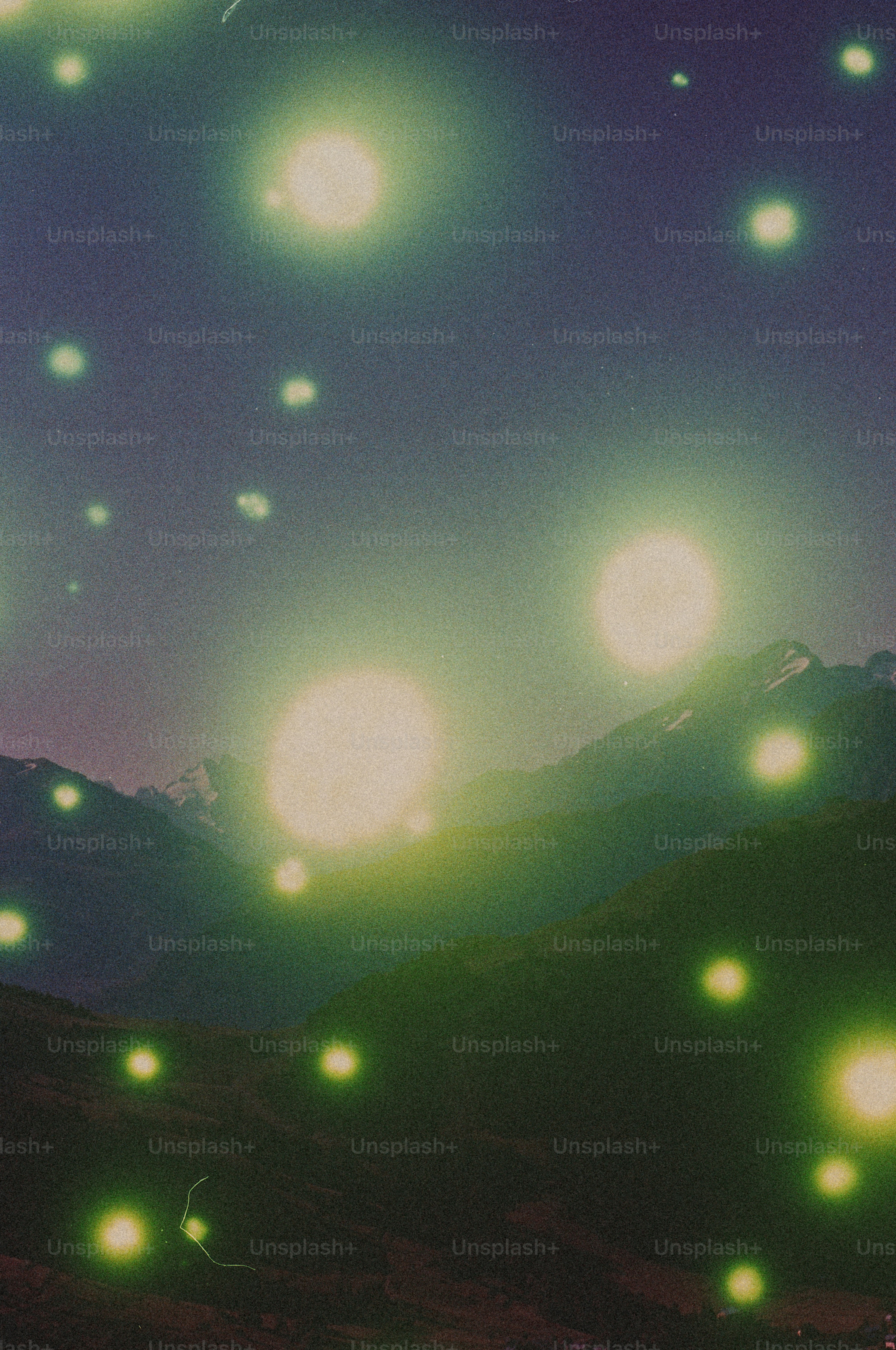 Glowing orbs over dark mountains at night