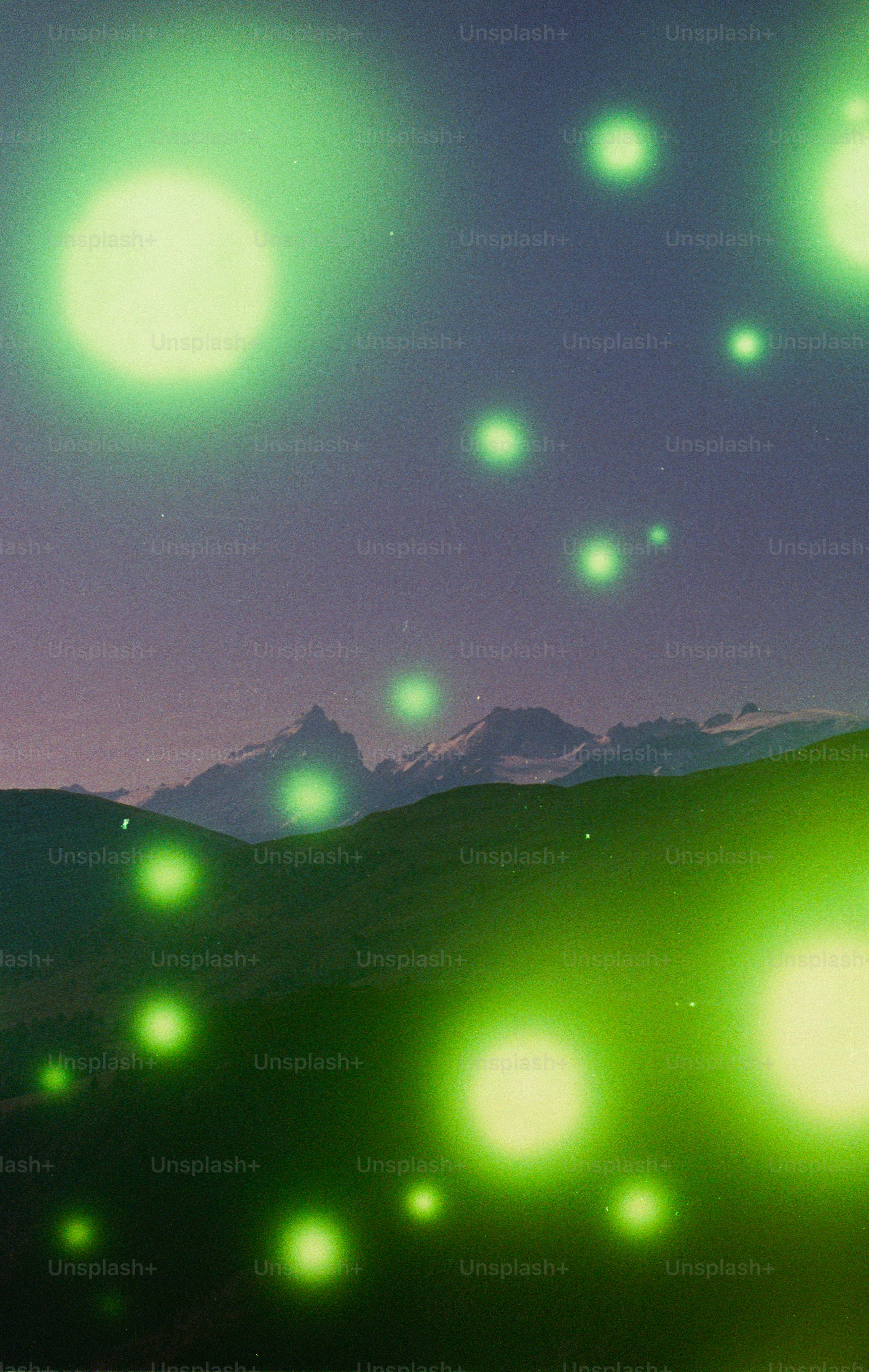 Green glowing orbs illuminate mountains under dark sky
