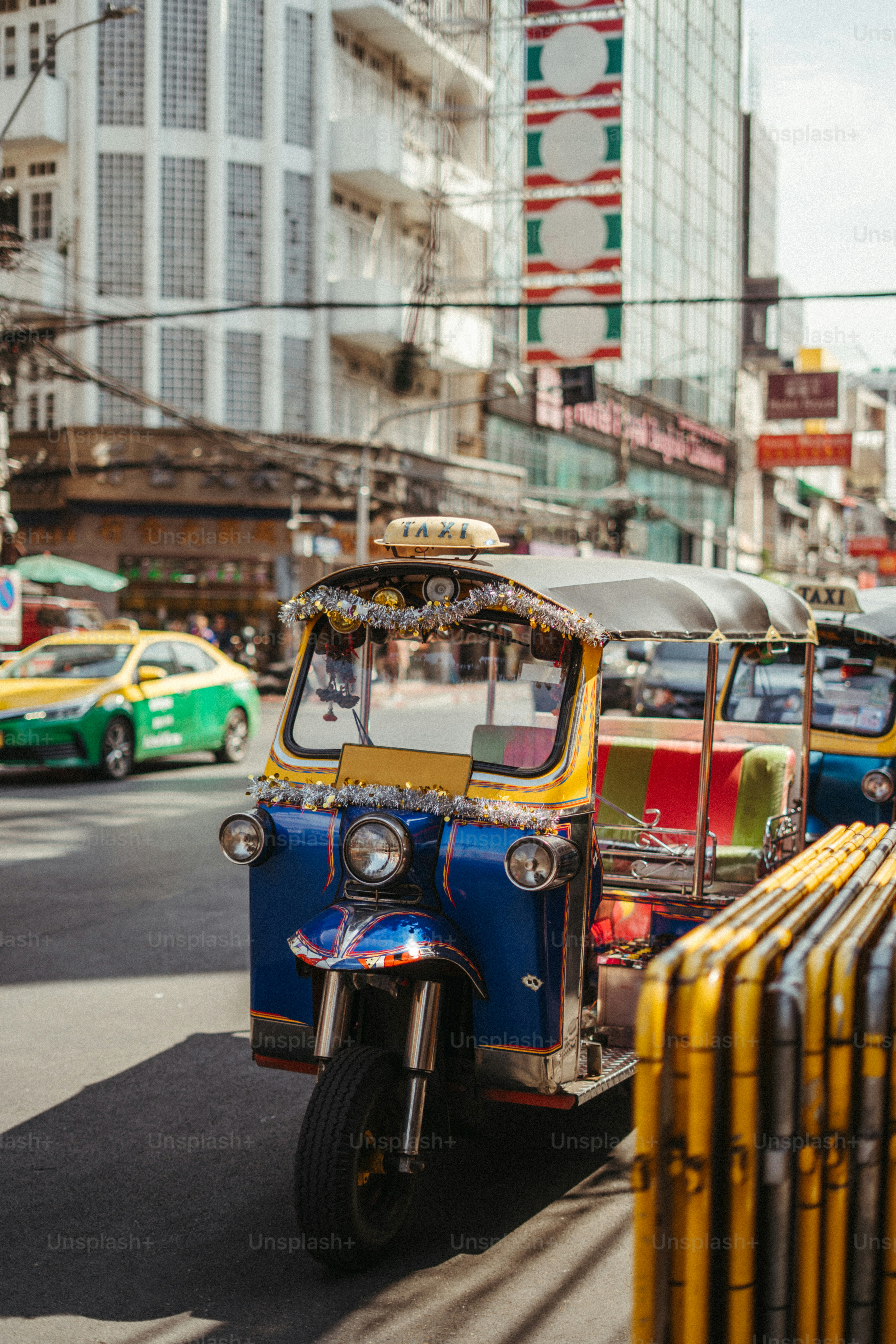 A blue and yellow tuk-tuk on a busy street in Bangkok, Thailand.