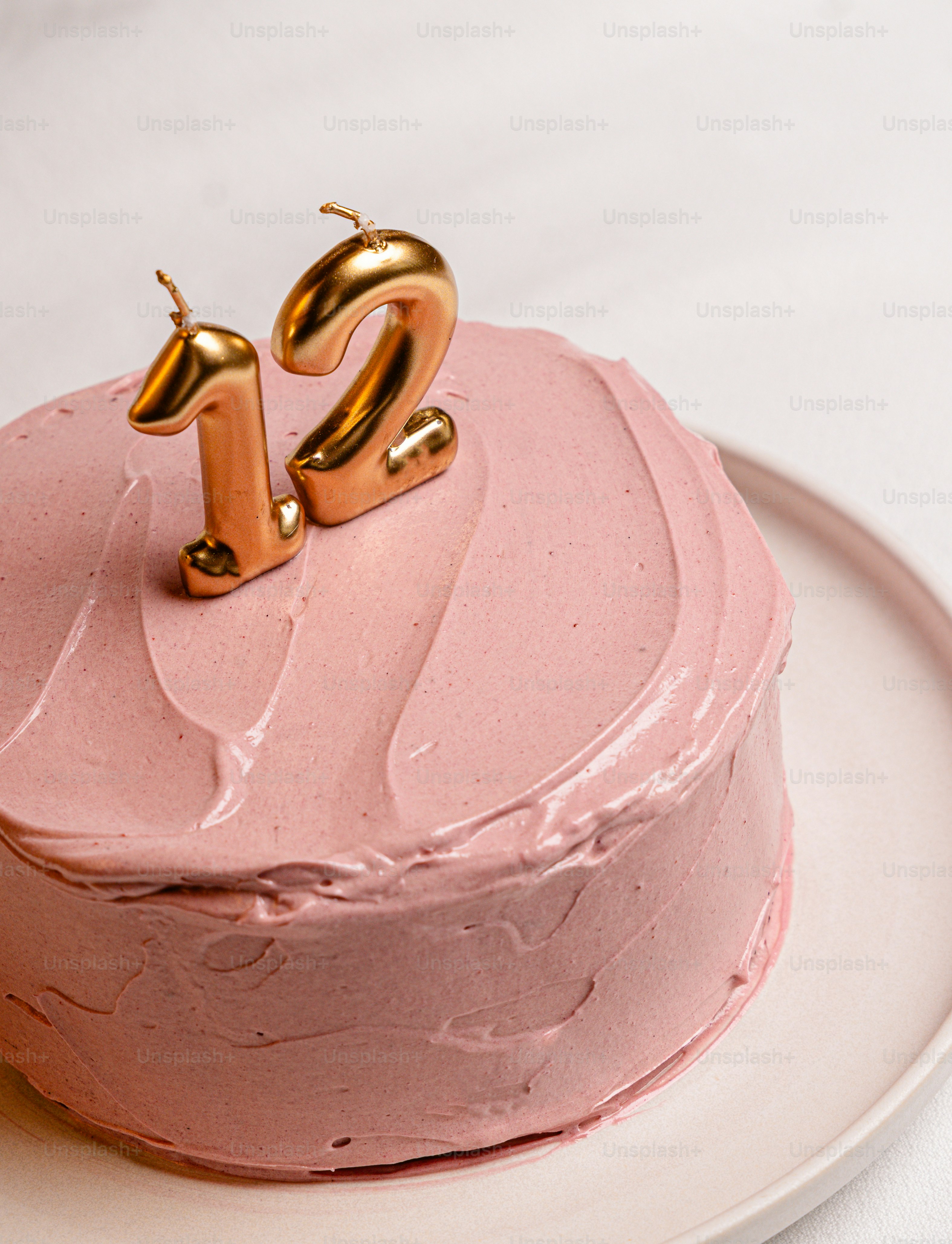 Pink frosted cake with golden "12" candles