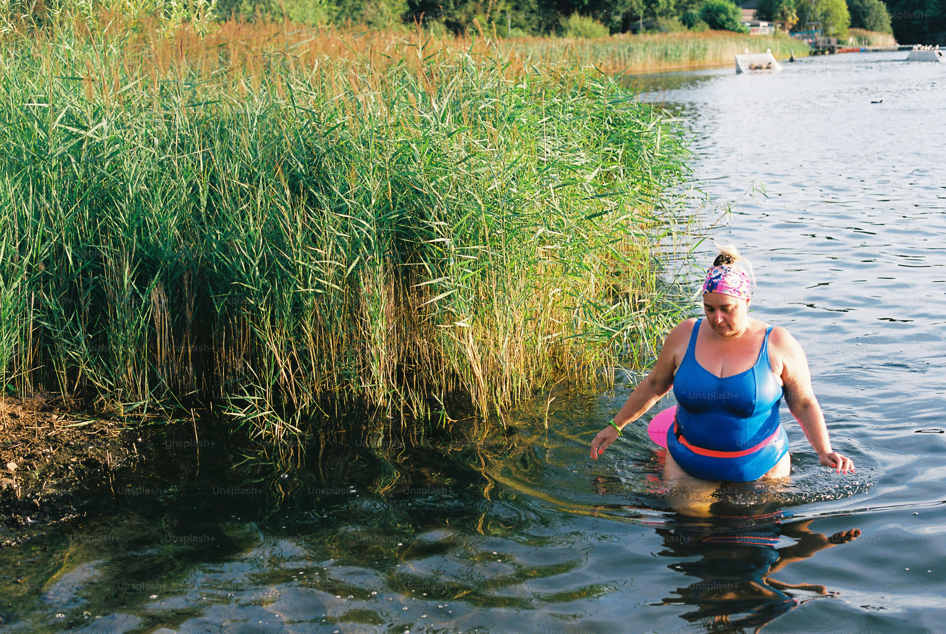 Swimmer wading from water by tall reeds