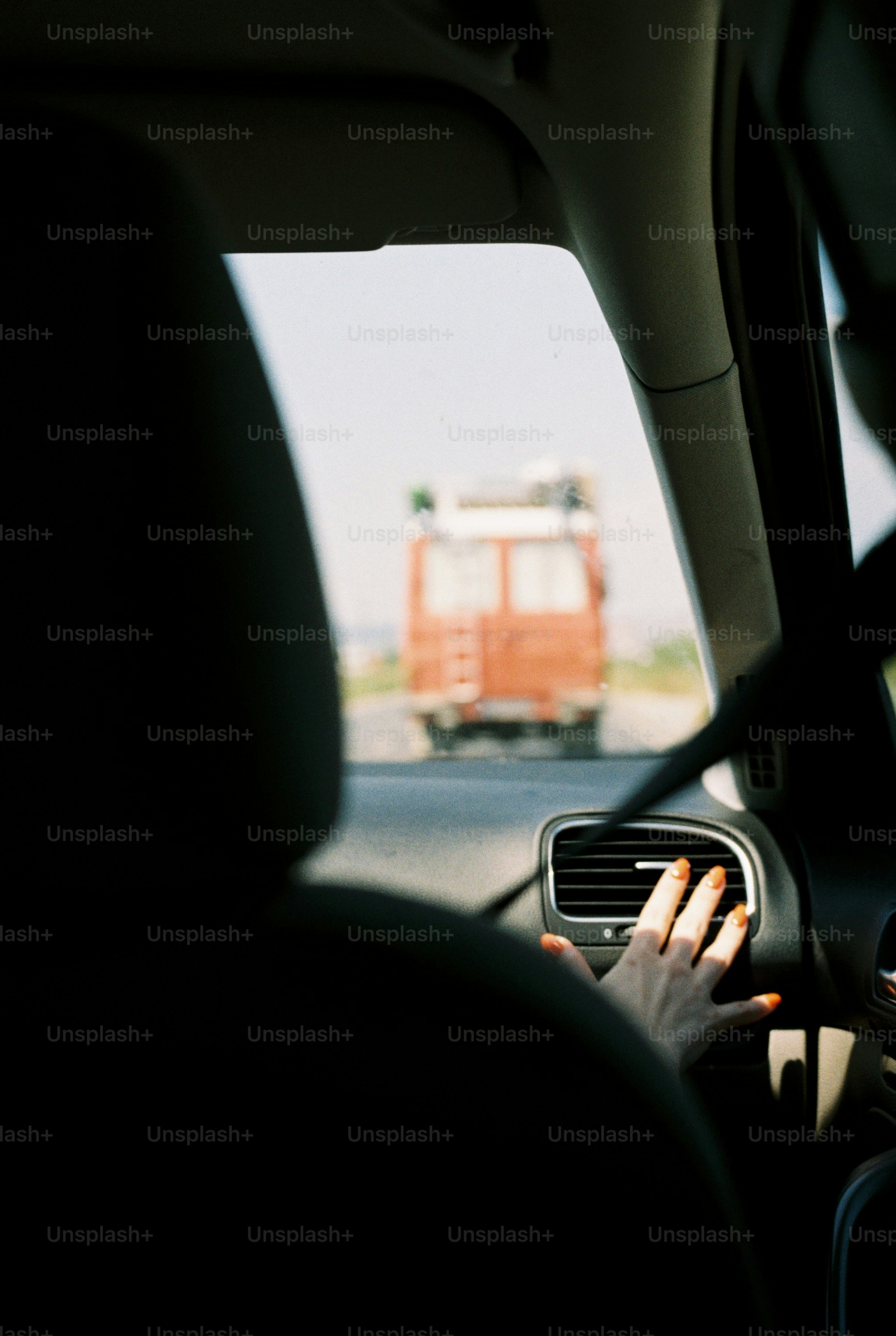 Hand on car air vent, truck on highway
