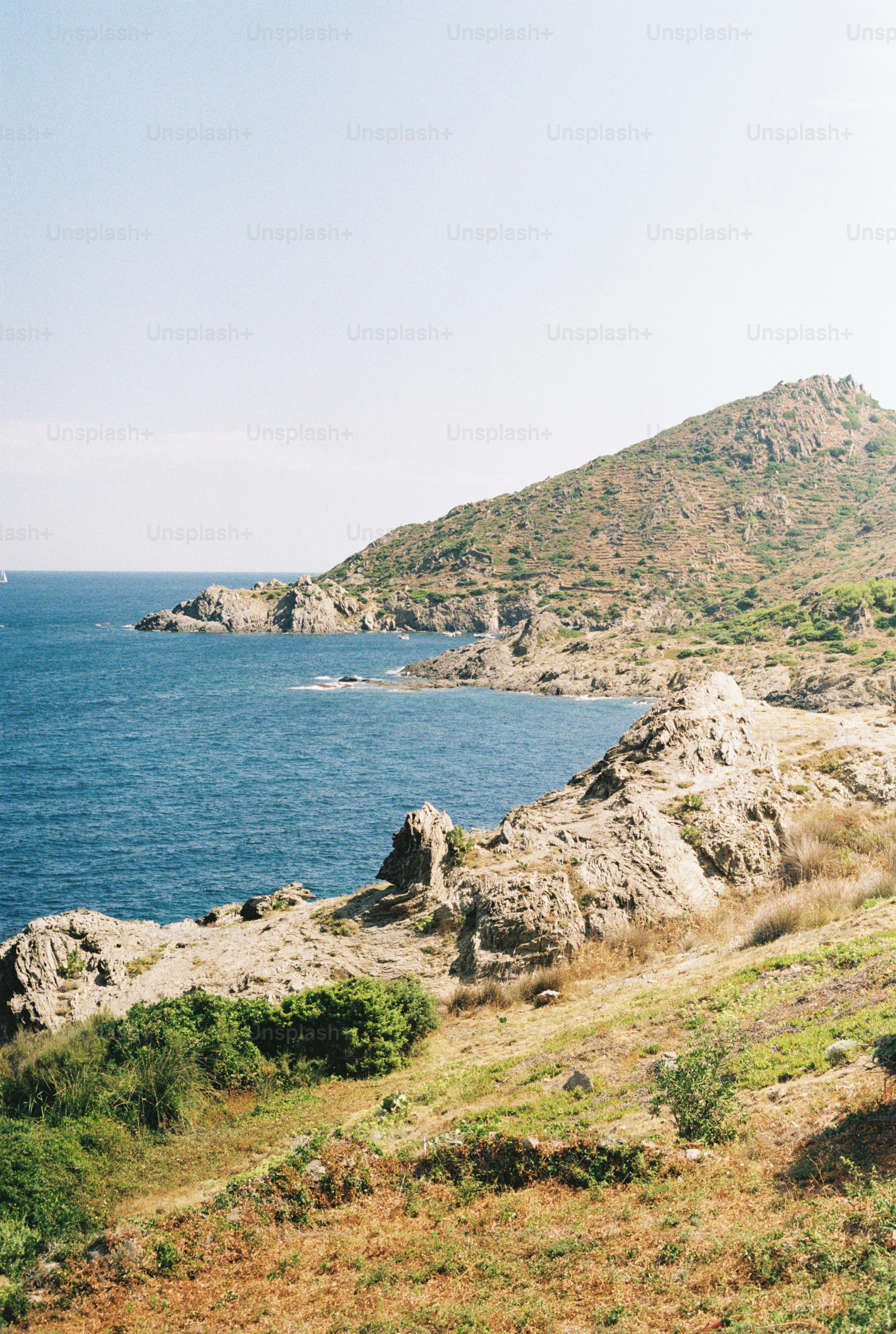 Rocky coastline meeting blue ocean under clear sky