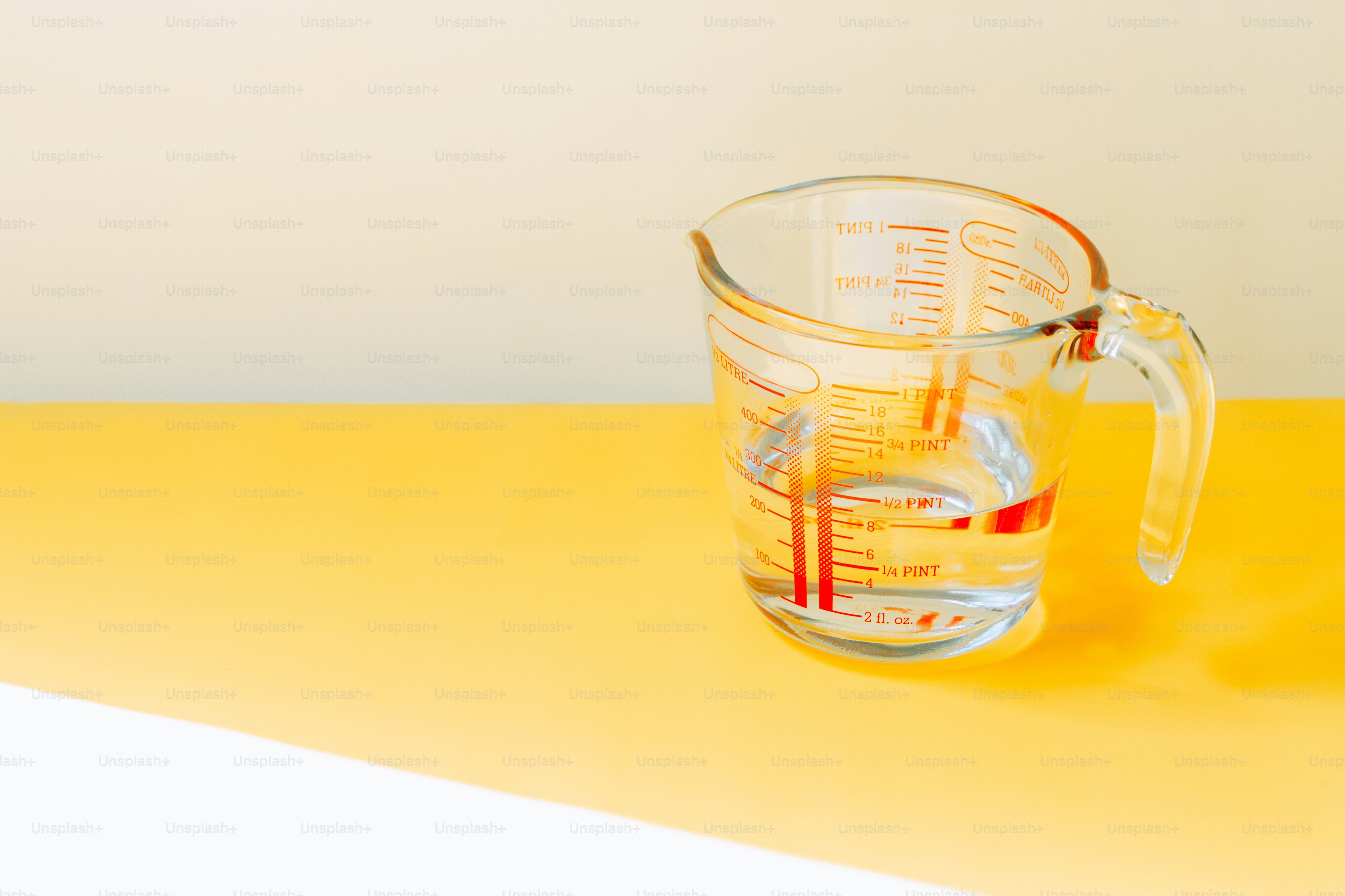 Measuring cup with water on yellow surface