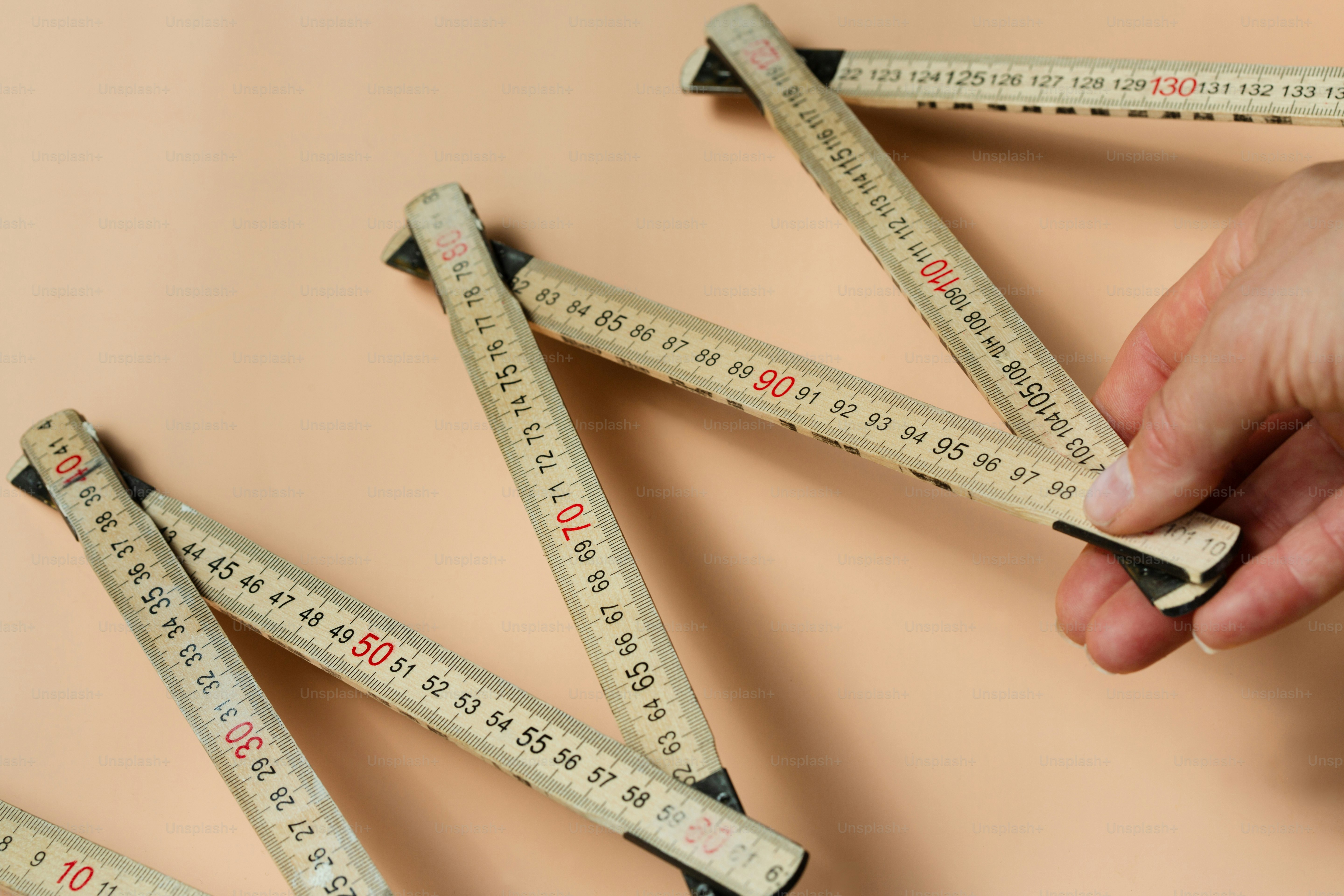 Hand unfolding wooden folding ruler on peach background