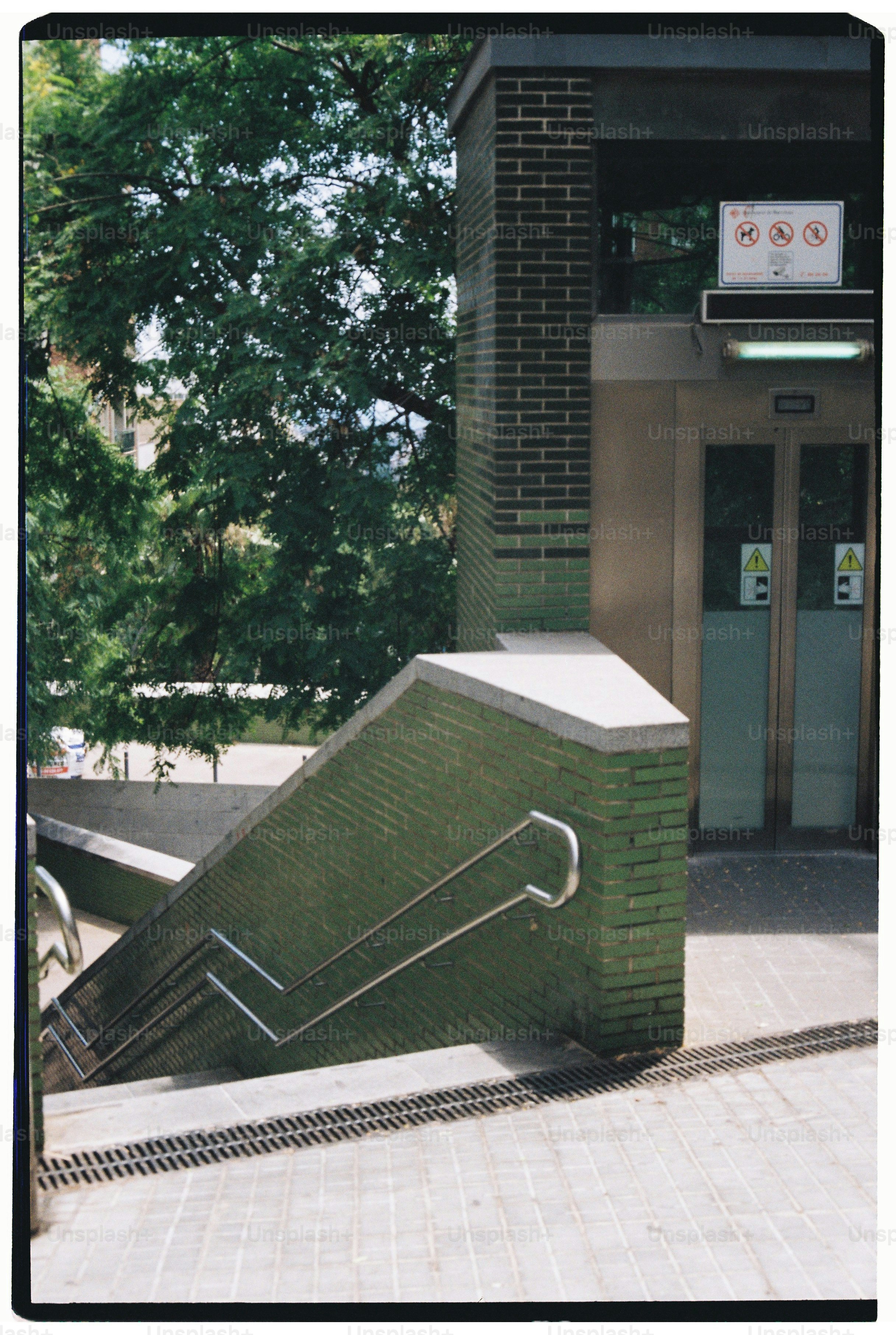 Outdoor staircase with green brick wall and trees