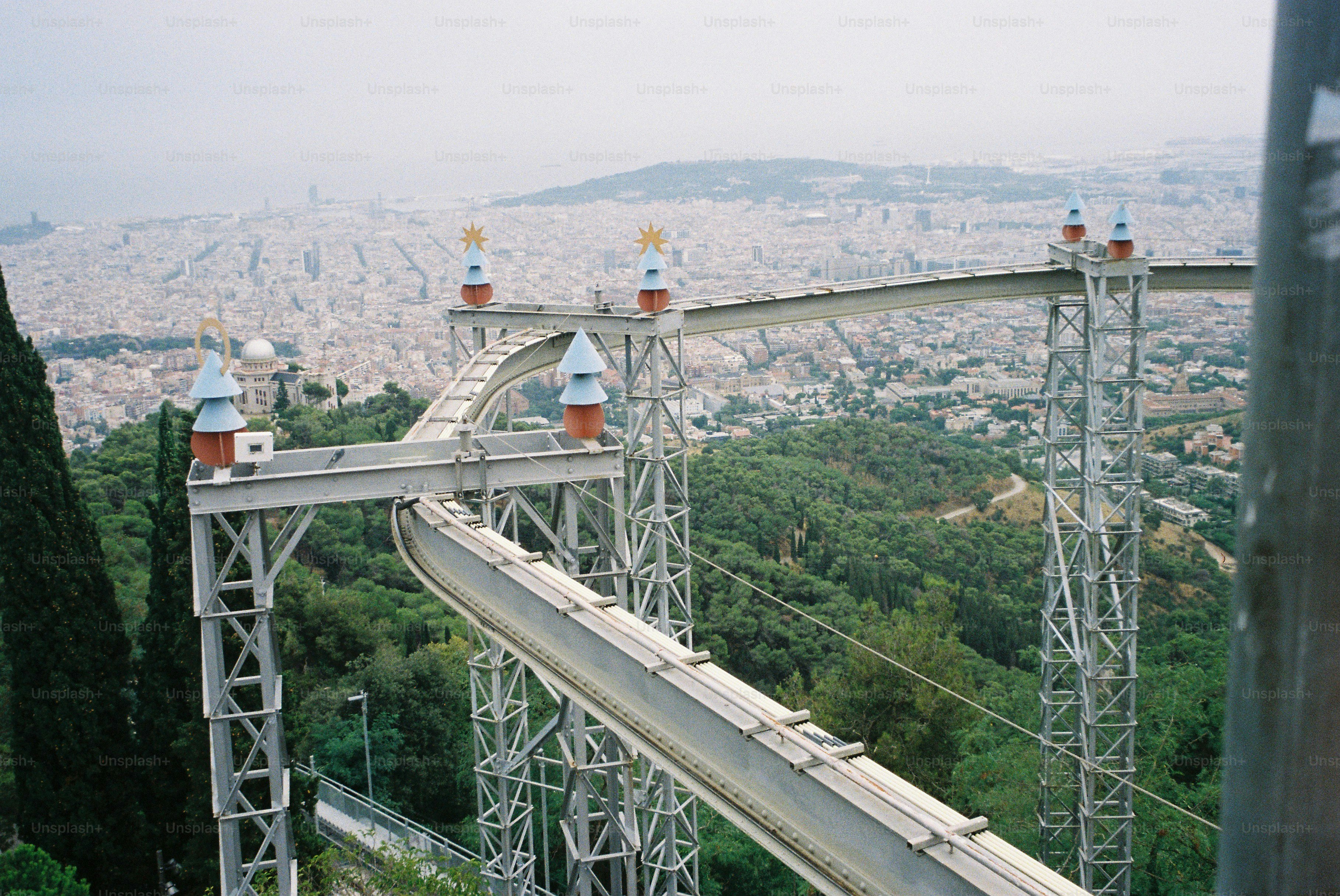 Roller coaster track winding through green hills above city