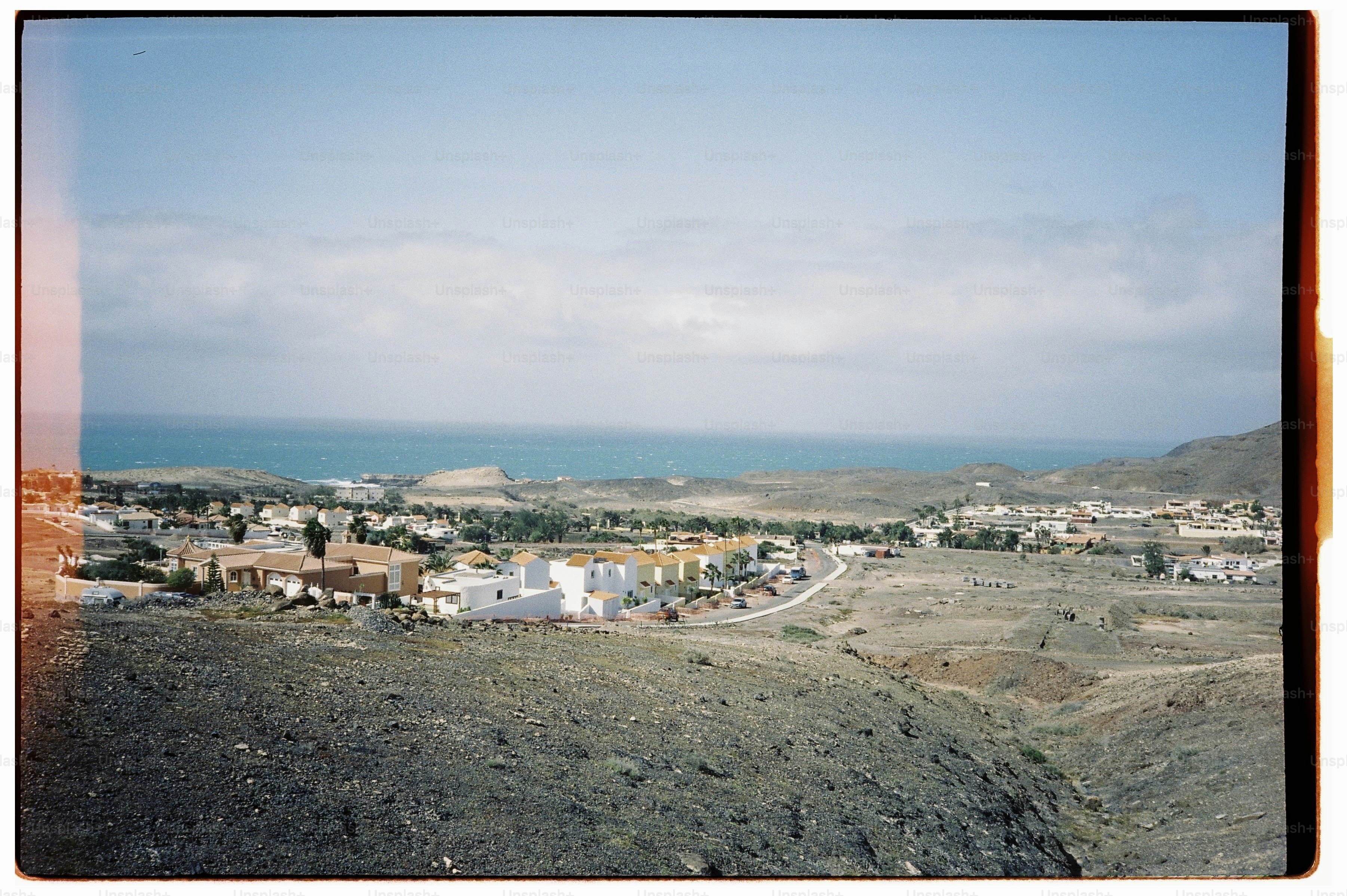 A coastal village with white houses near the blue sea under a cloudy sky.