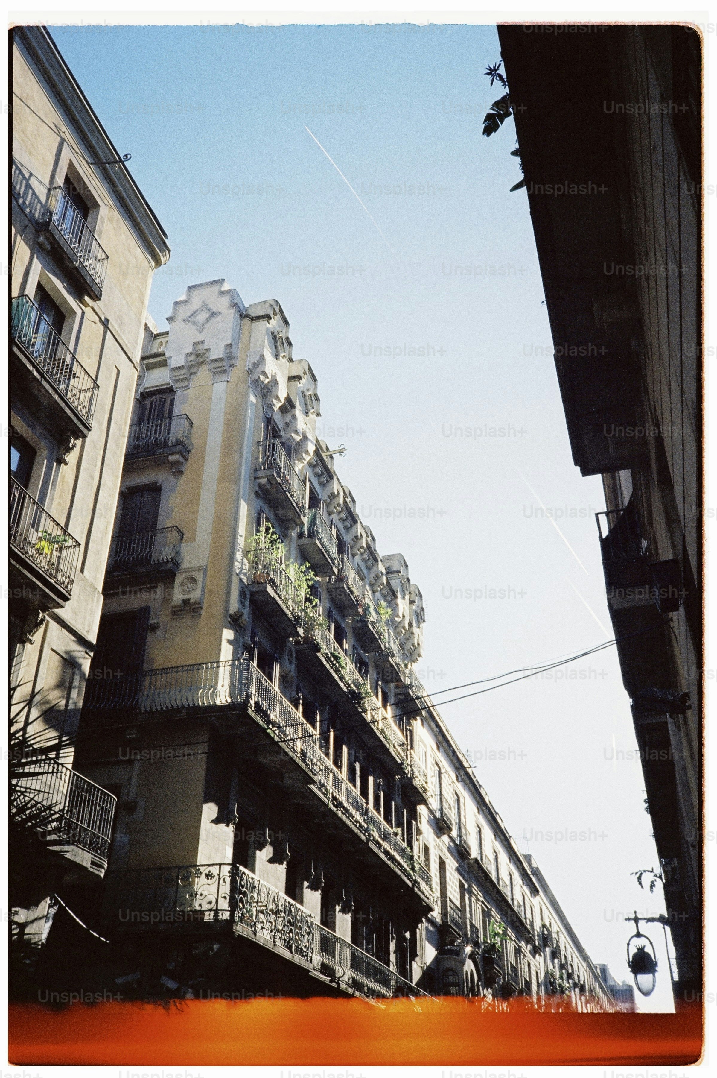 Low-angle view of ornate historic apartment buildings with balconies along a narrow street