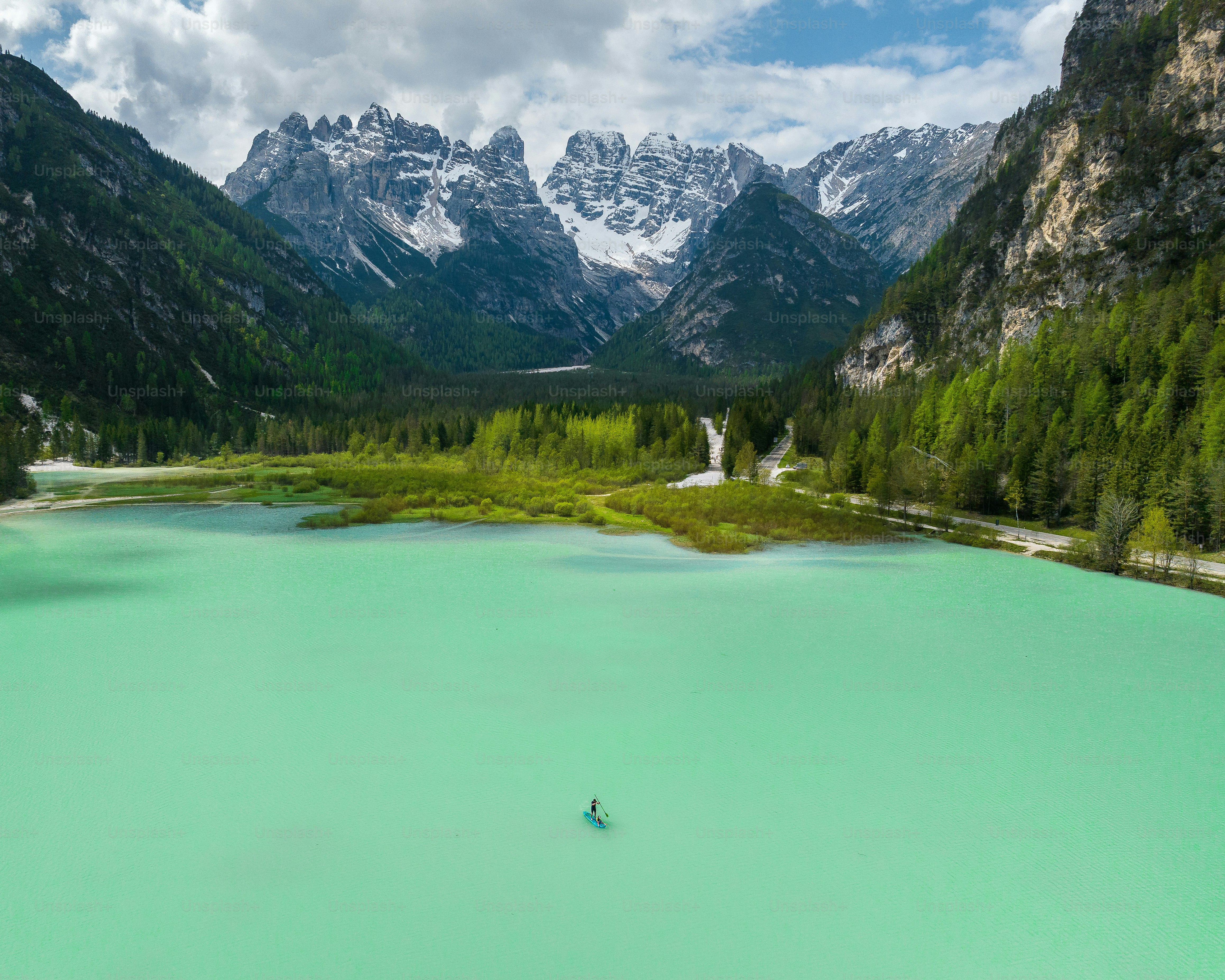 A person on a paddleboard in the turquoise water of Lake Landro in the Dolomites