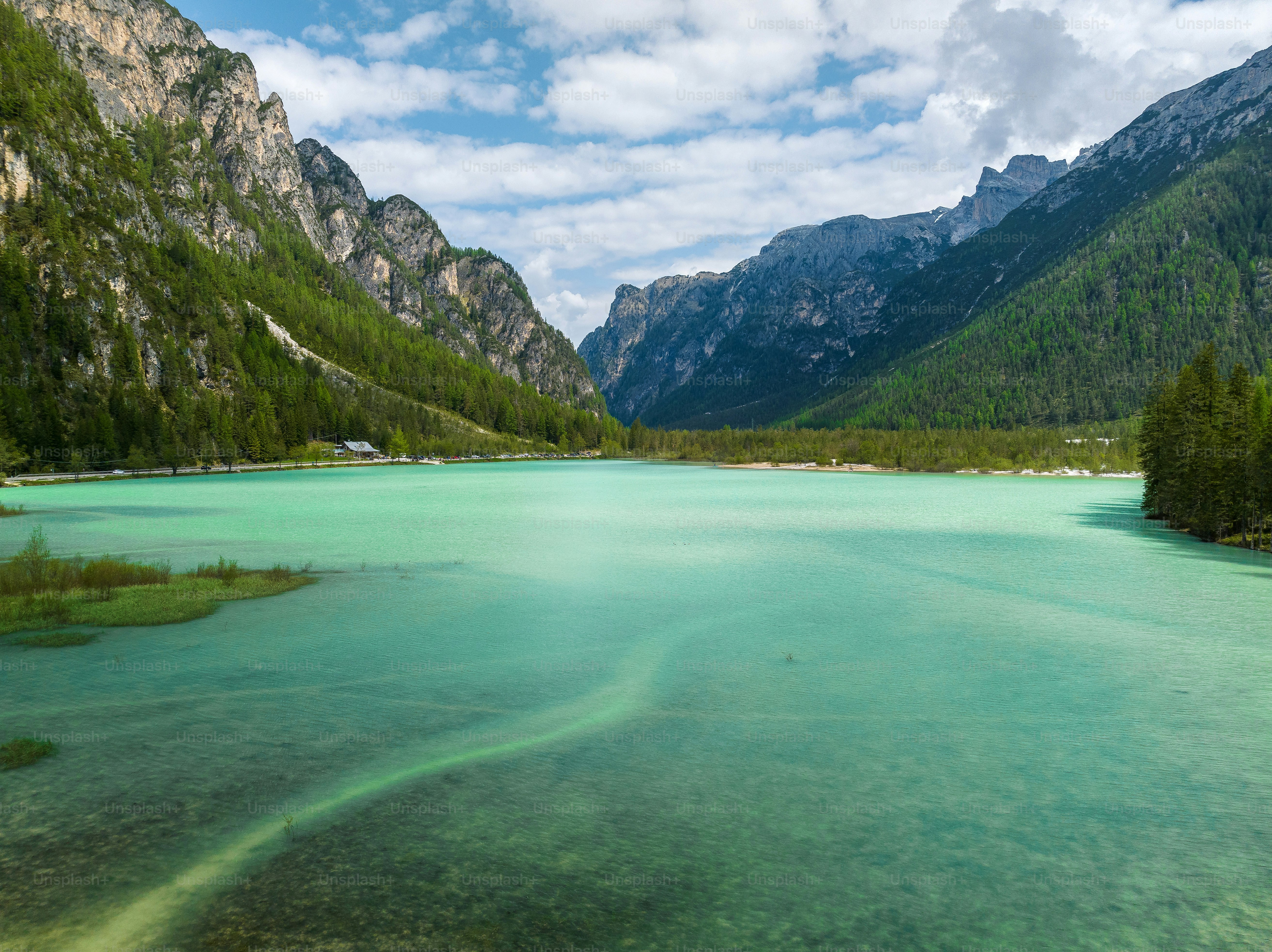 A turquoise lake surrounded by steep forested mountains in the Dolomites, Italy