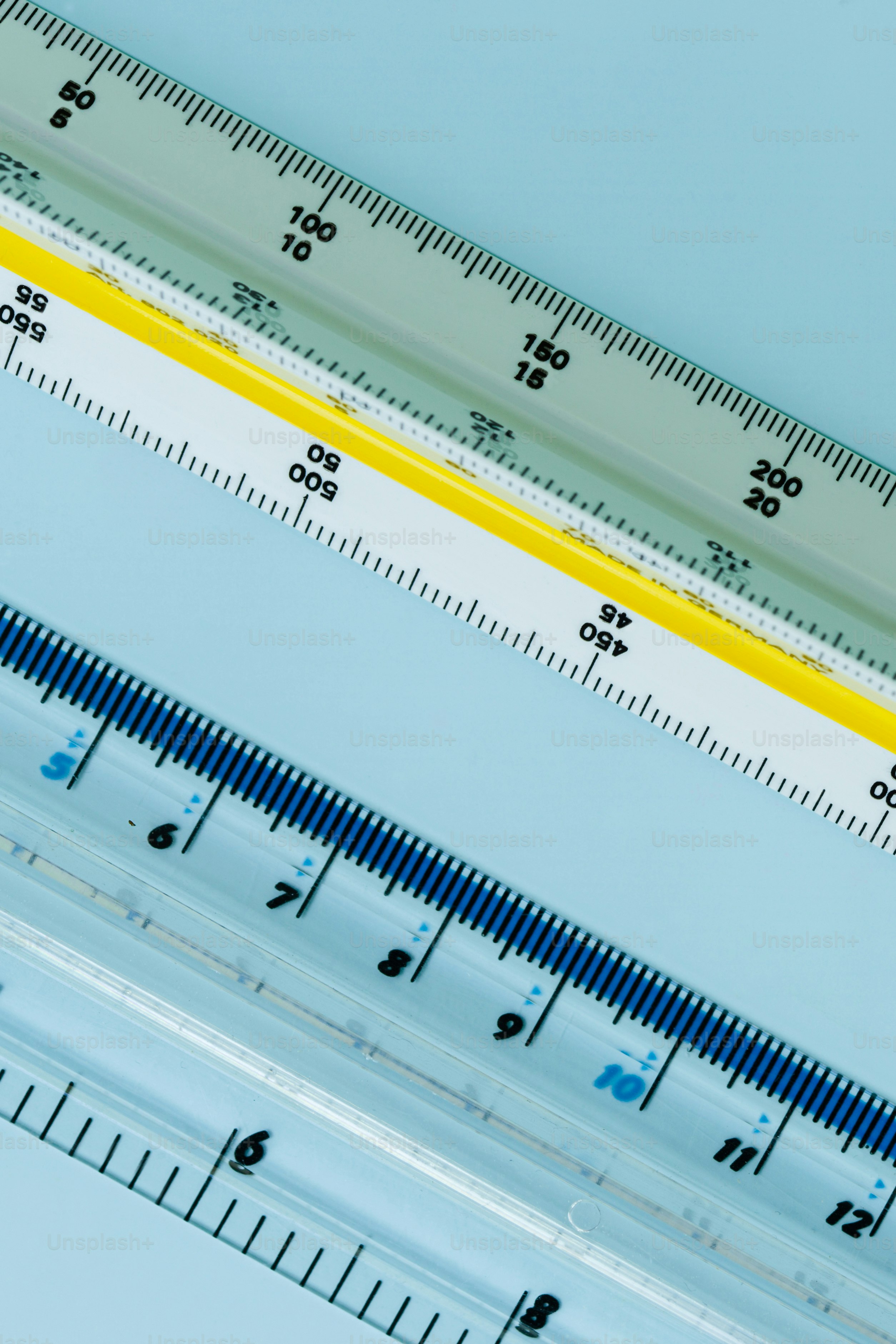 Three architectural triangular scale rulers with yellow, white, and clear plastic bodies.