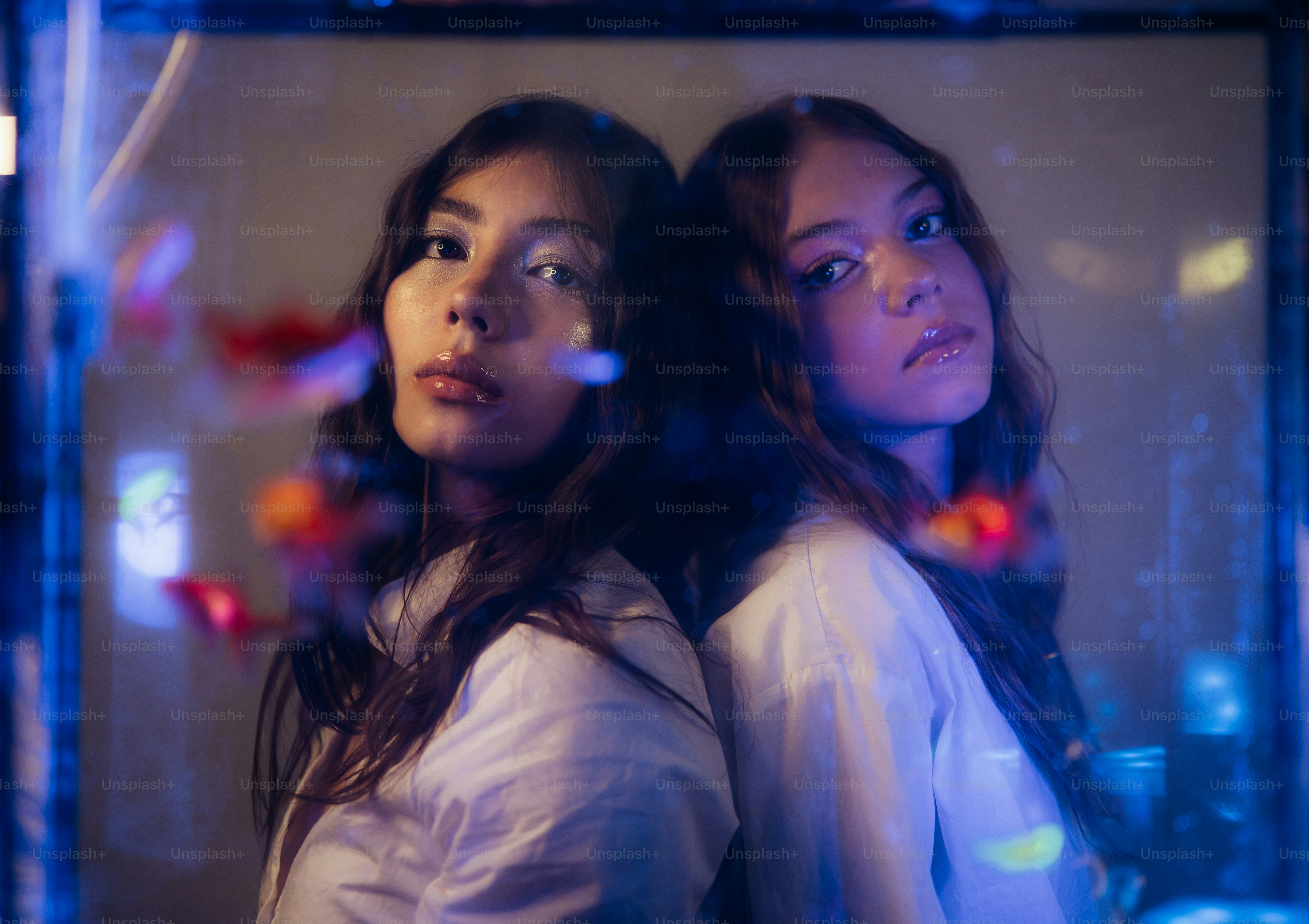 Women standing back to back in blue and orange light