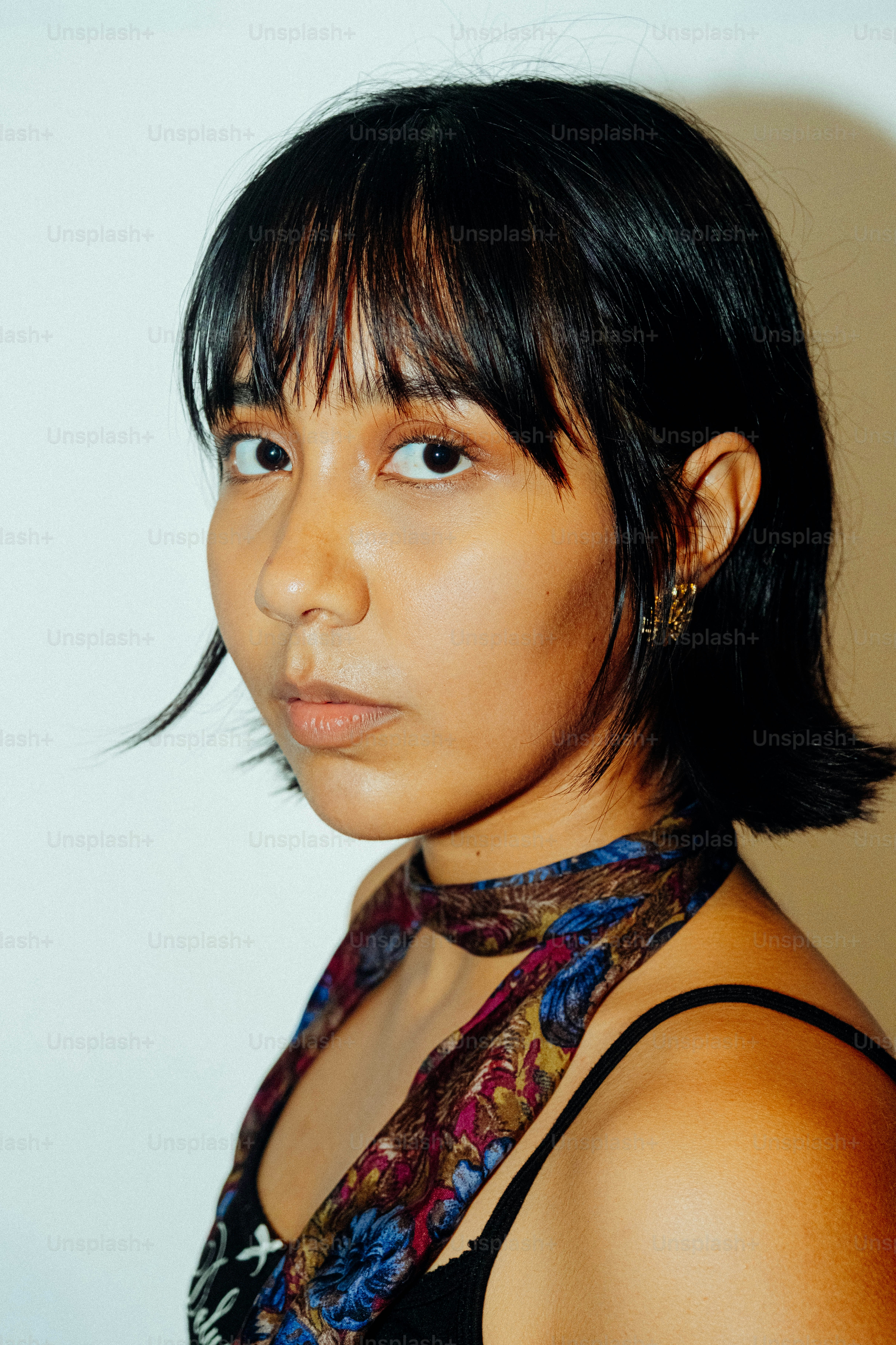 A person with dark hair and a patterned scarf around their neck
