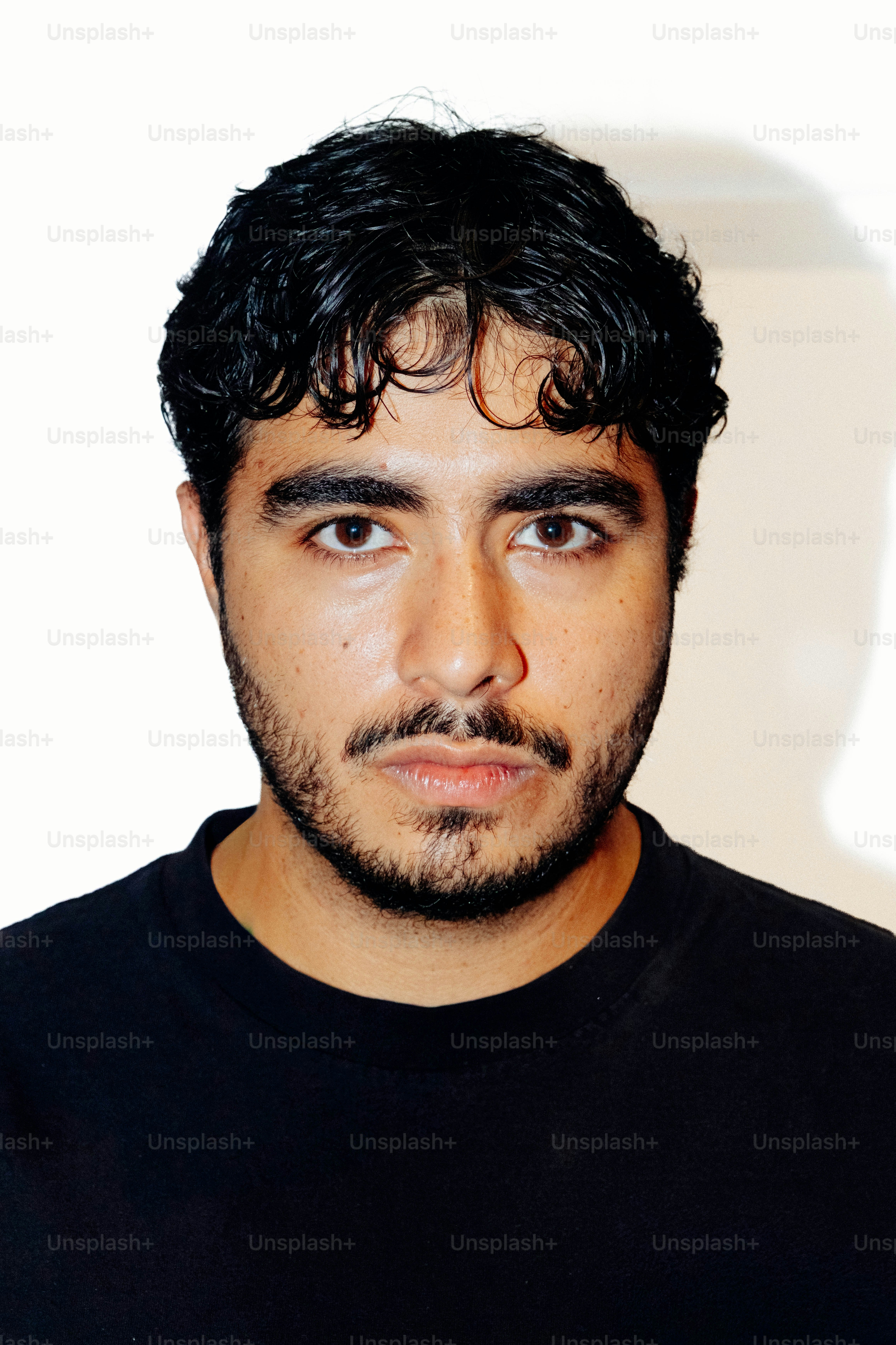 A man with dark curly hair and a beard in a black t-shirt