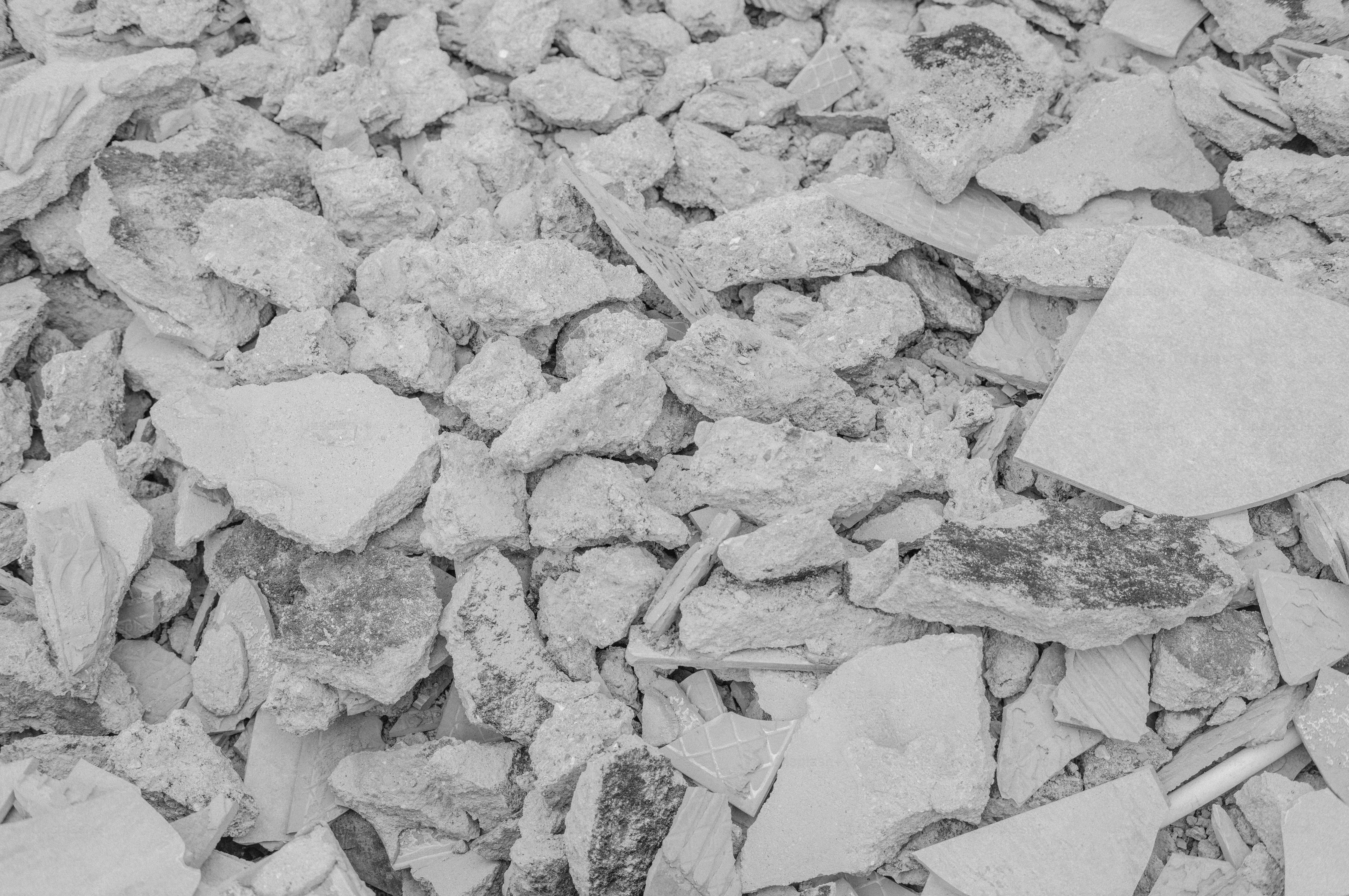 A pile of broken grey concrete rubble and fragments of ceramic tile