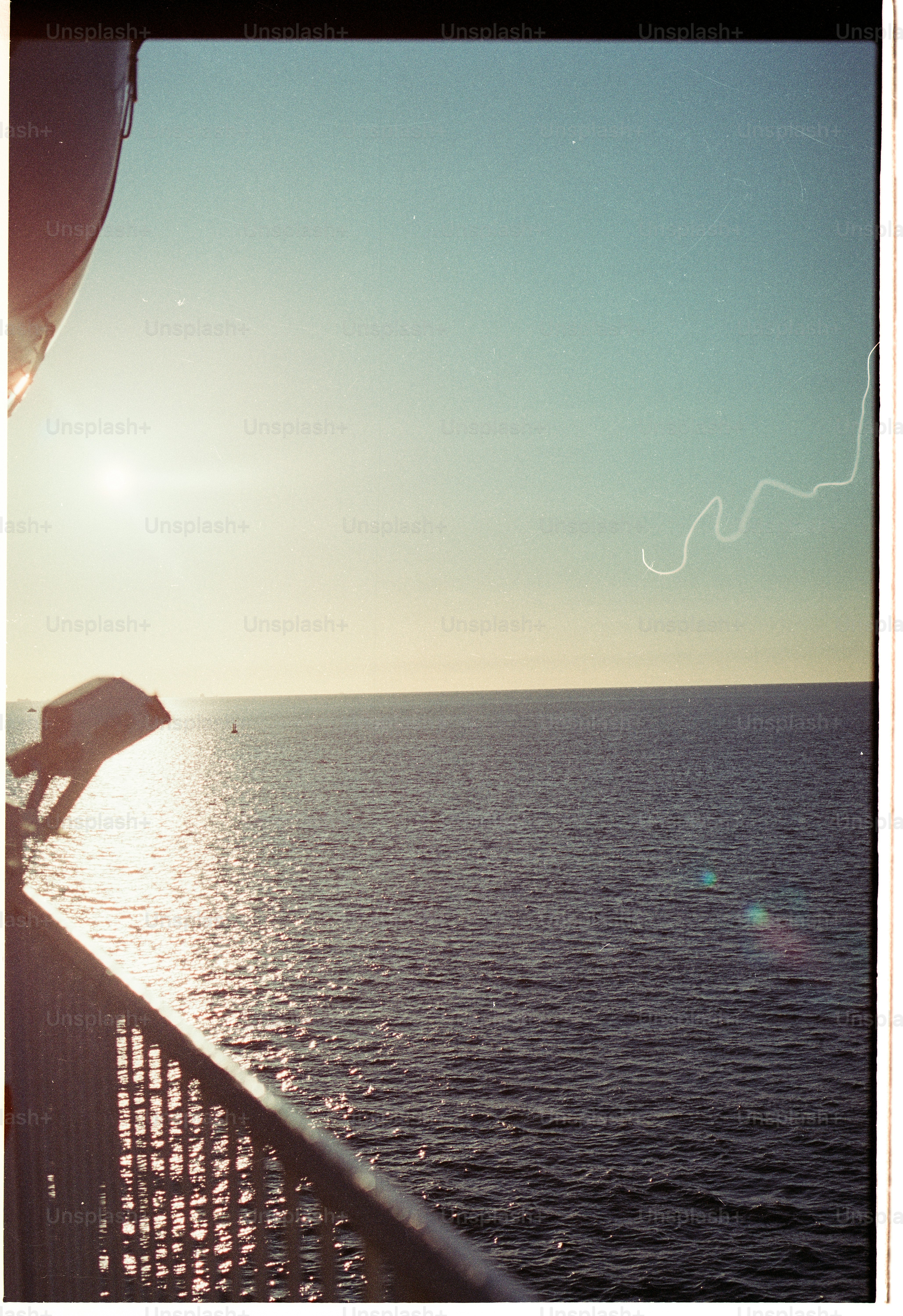 A view of the open sea from a ship railing at golden hour
