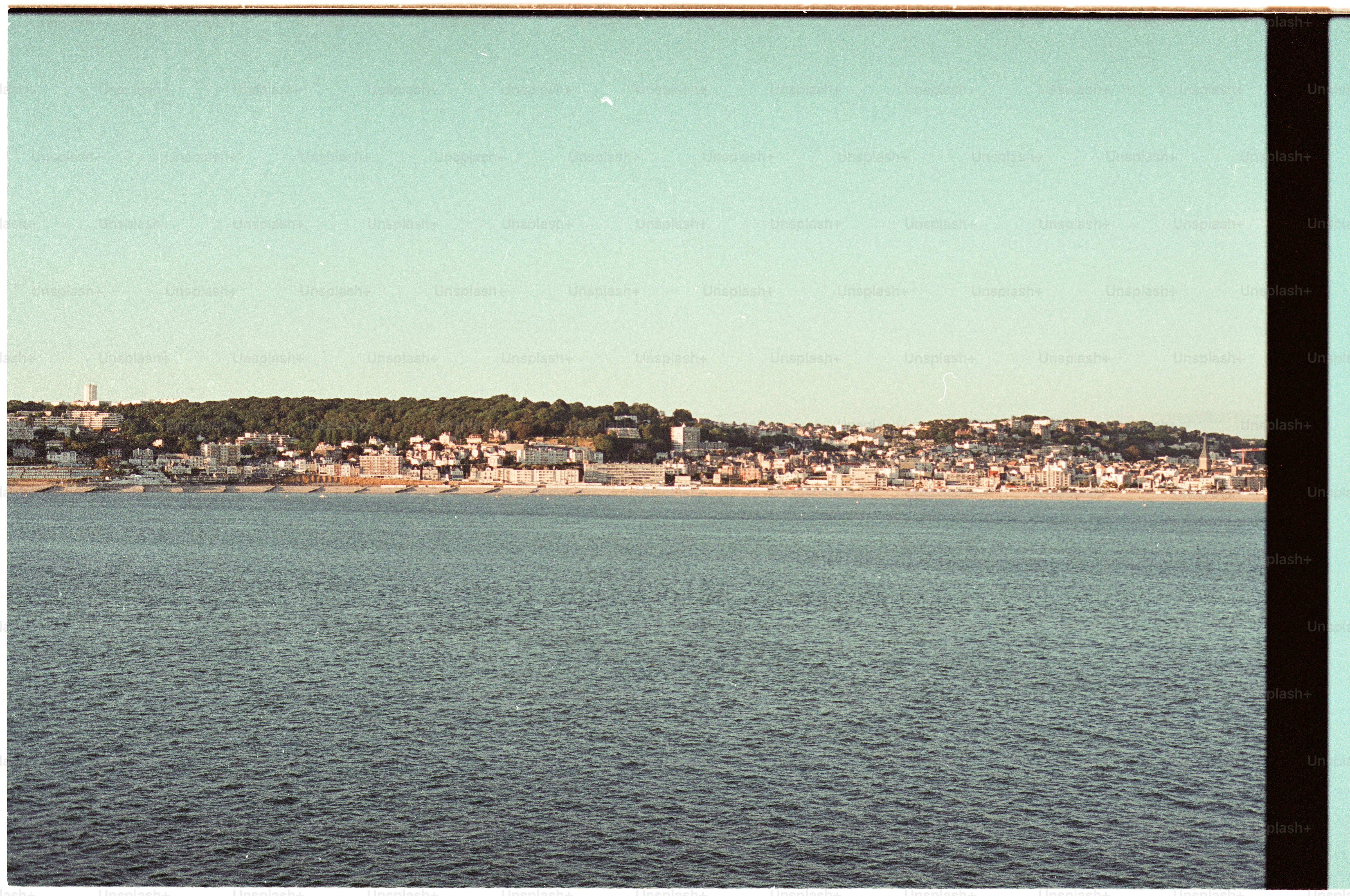 A coastal town with buildings along a beach under a clear blue sky