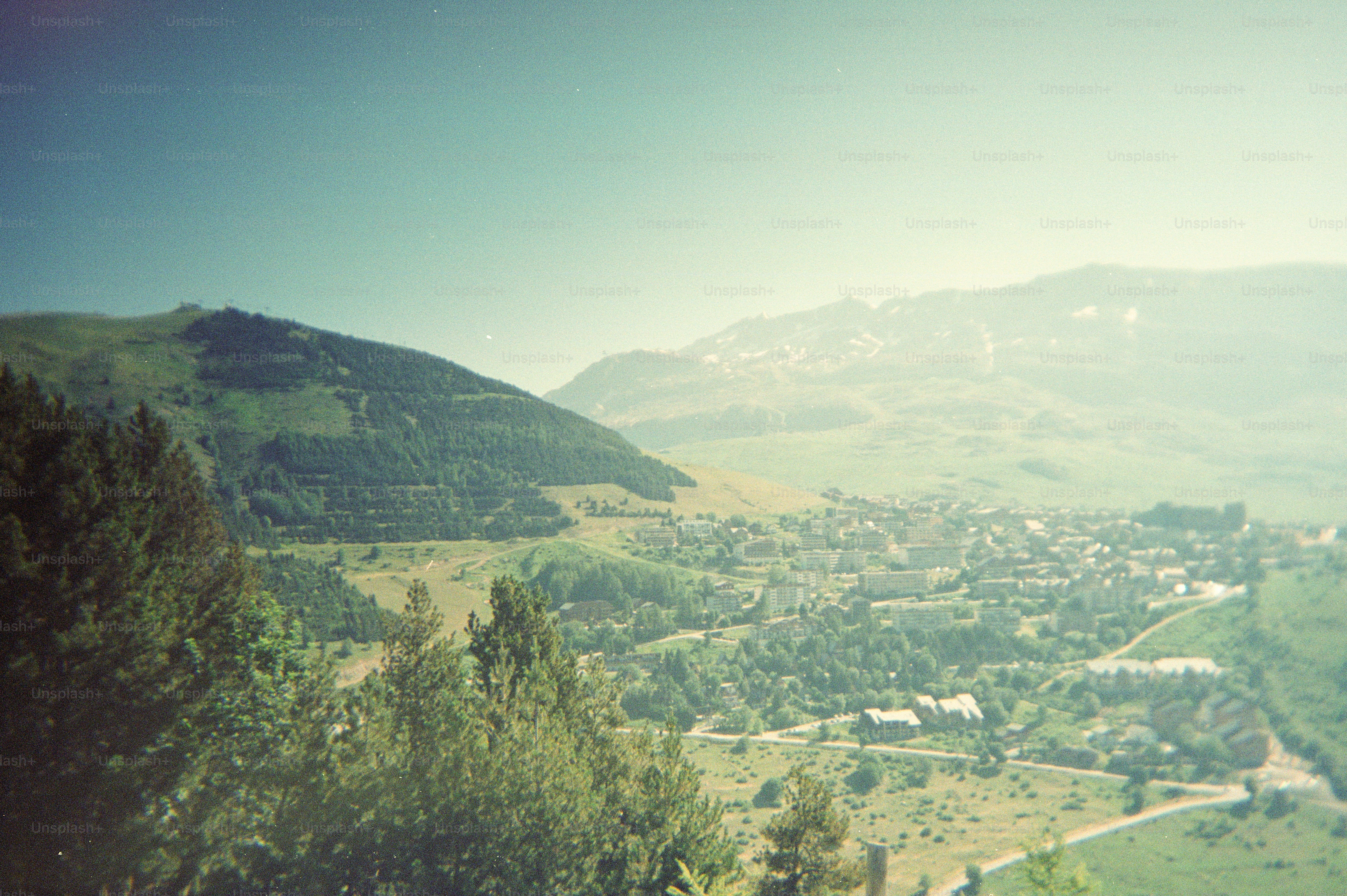 A town nestled in a green valley surrounded by rolling mountain slopes